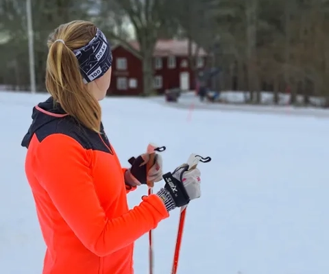 Längdskidåkare vid Högalidens fritidsområde. Snö och vinter, en åkare med orange jacka och svarta byxor.