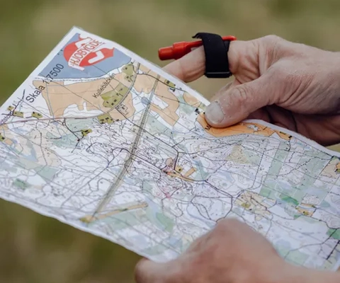 Händer som håller i en orienteringskarta