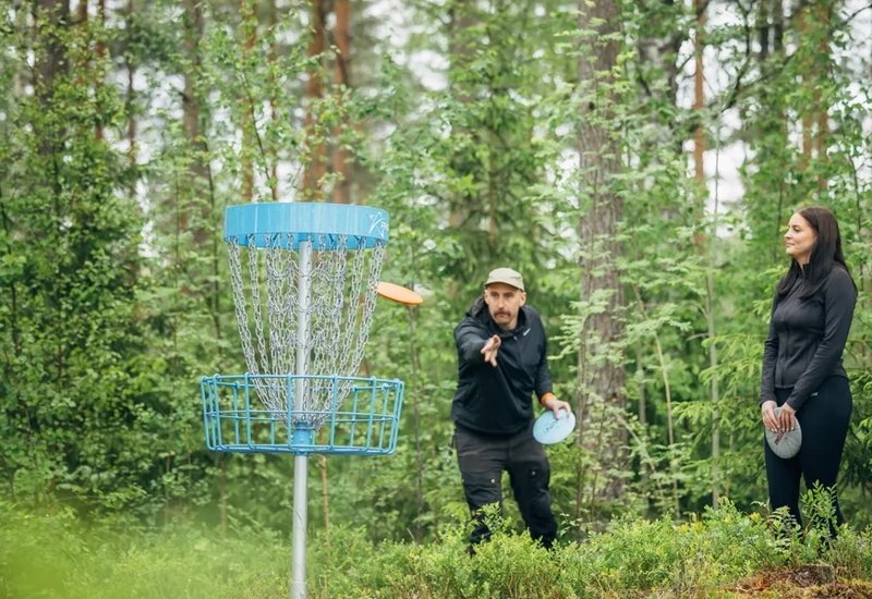 Människor som aktiverar sig i ett naturområde med frisbeegolf.