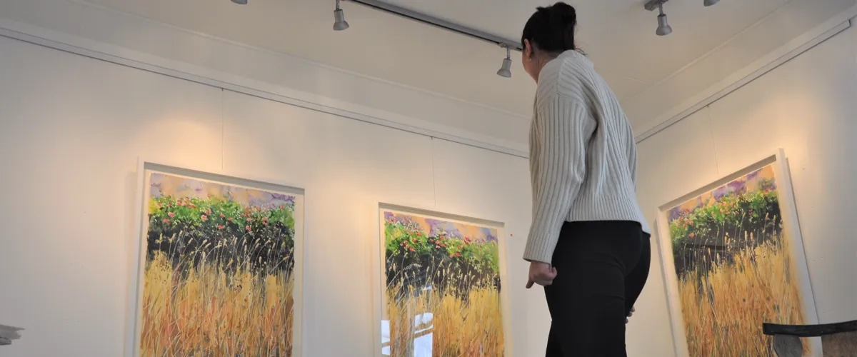 kvinna ser på tavlor i galleri