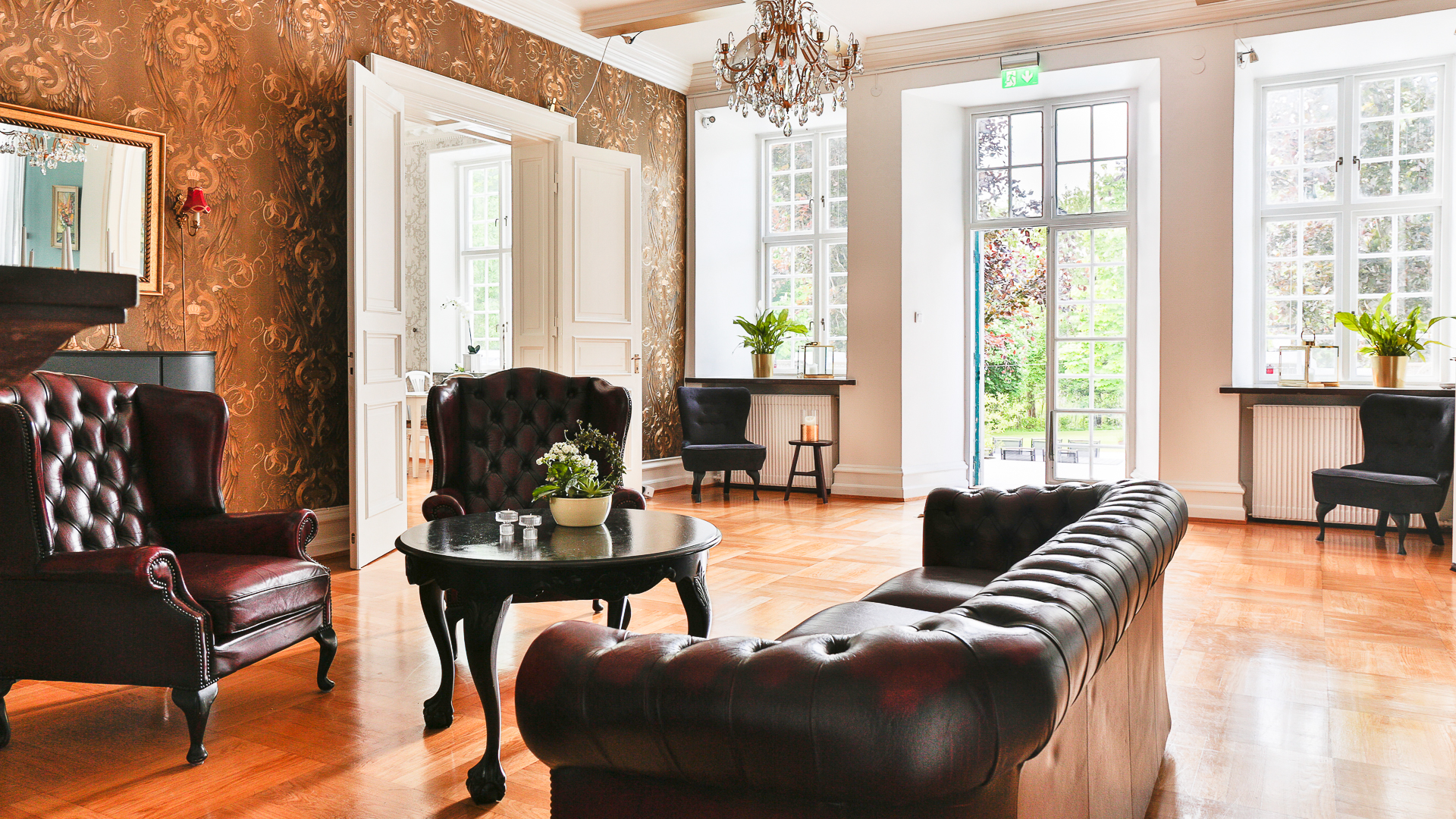 Rum med sittgrupp i skinn och dörrar ut mot trädgården