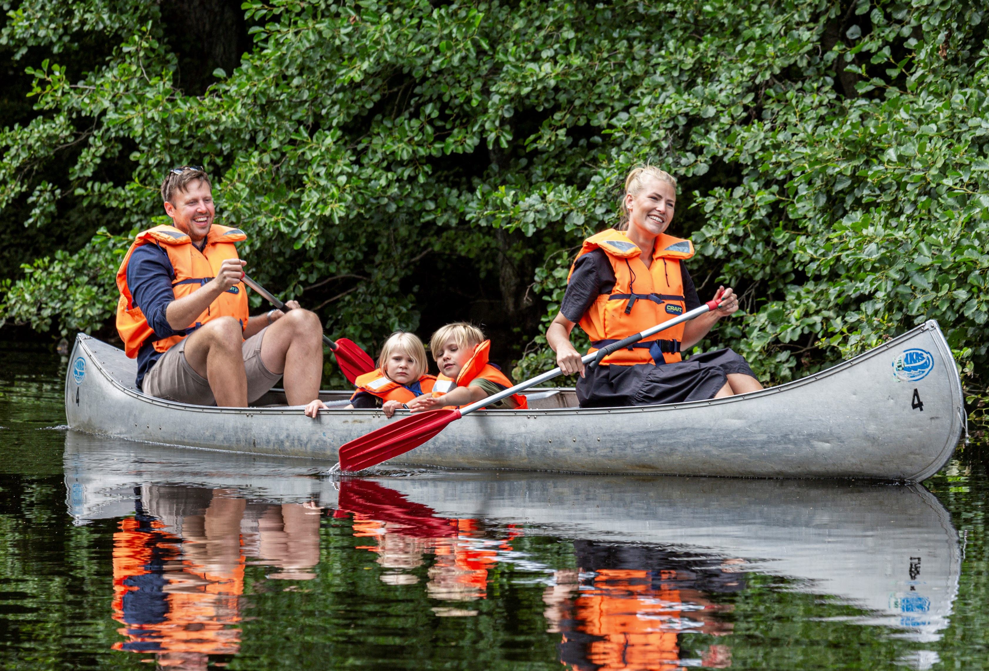 Familj med två barn paddlar kanot