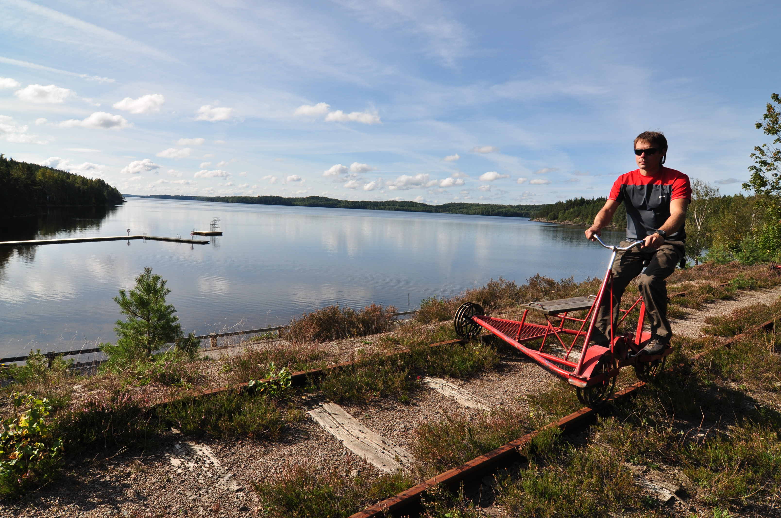 Man riding a rail bike along a lake.