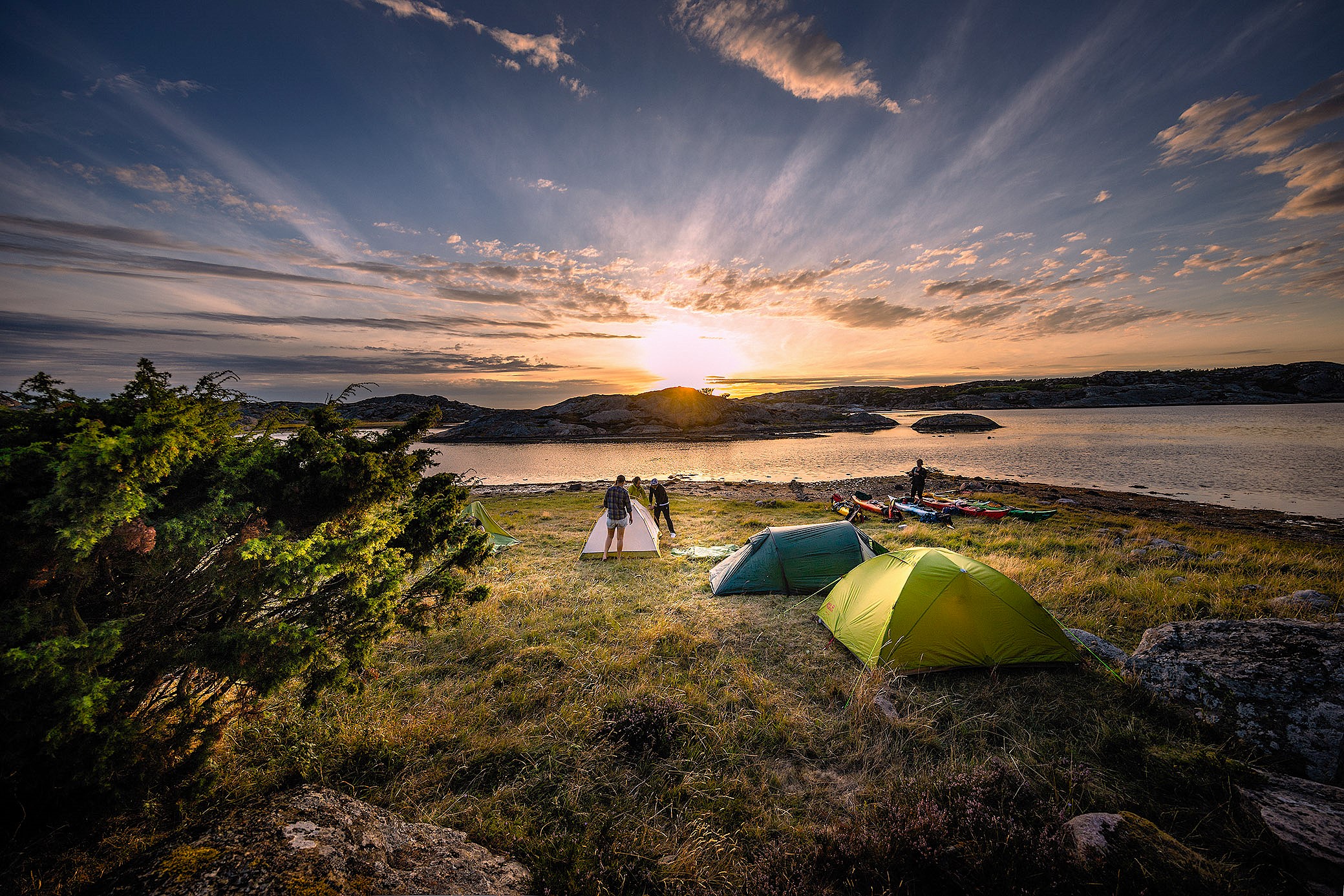 En grupp kajakpaddlare har satt upp tält på en ö och njuter av en vacker solnedgång; Balanspunkten – Kajak i Grundsund