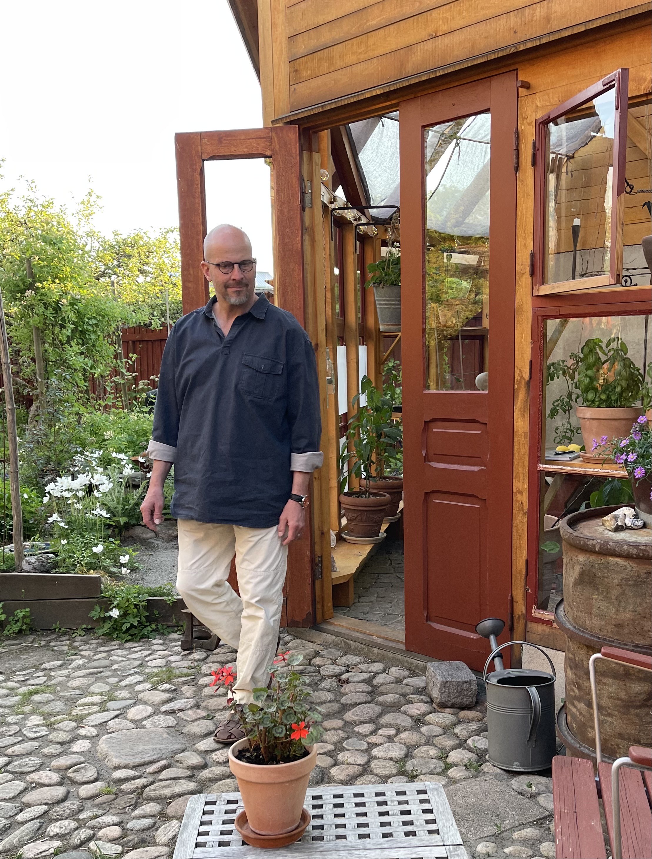 En man promenerar ut ur ett växthus tillö trädgården hos Lilla Hotellet i Tranemo