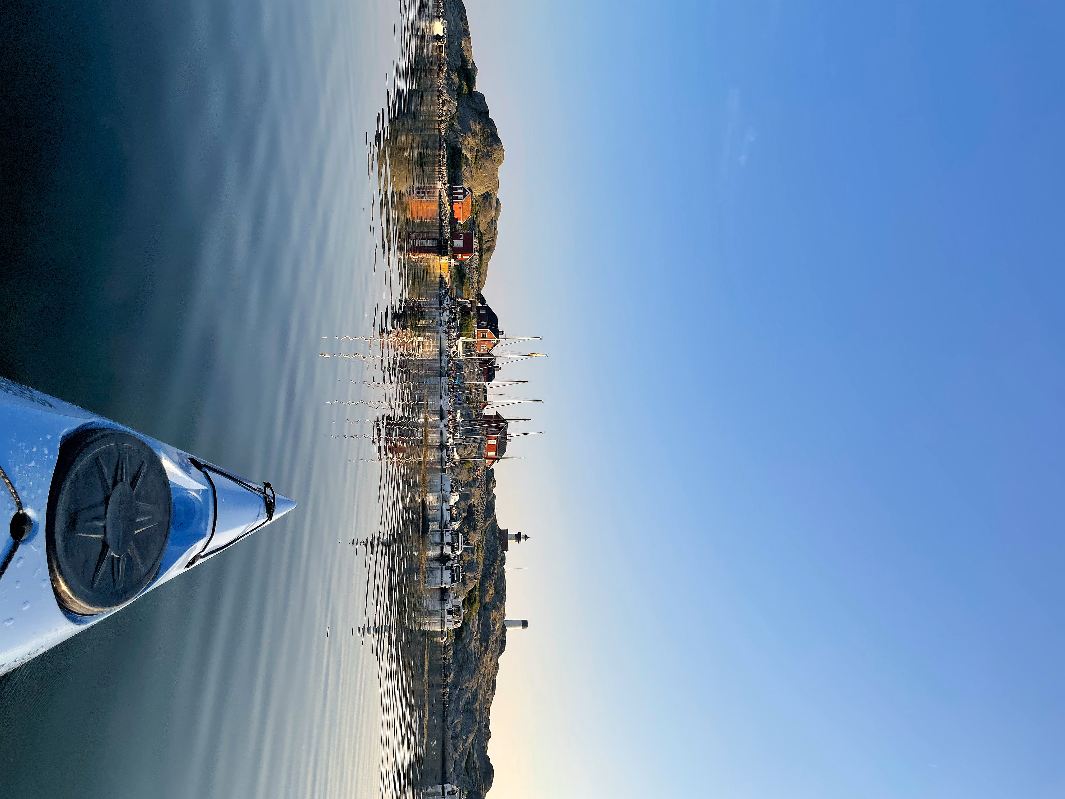 The bow of a kayak in beautiful evening light in front of an inhabited island