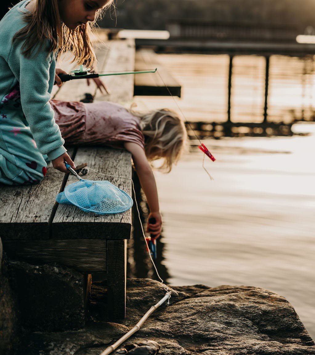 Two children on a pier fishing for crabs.