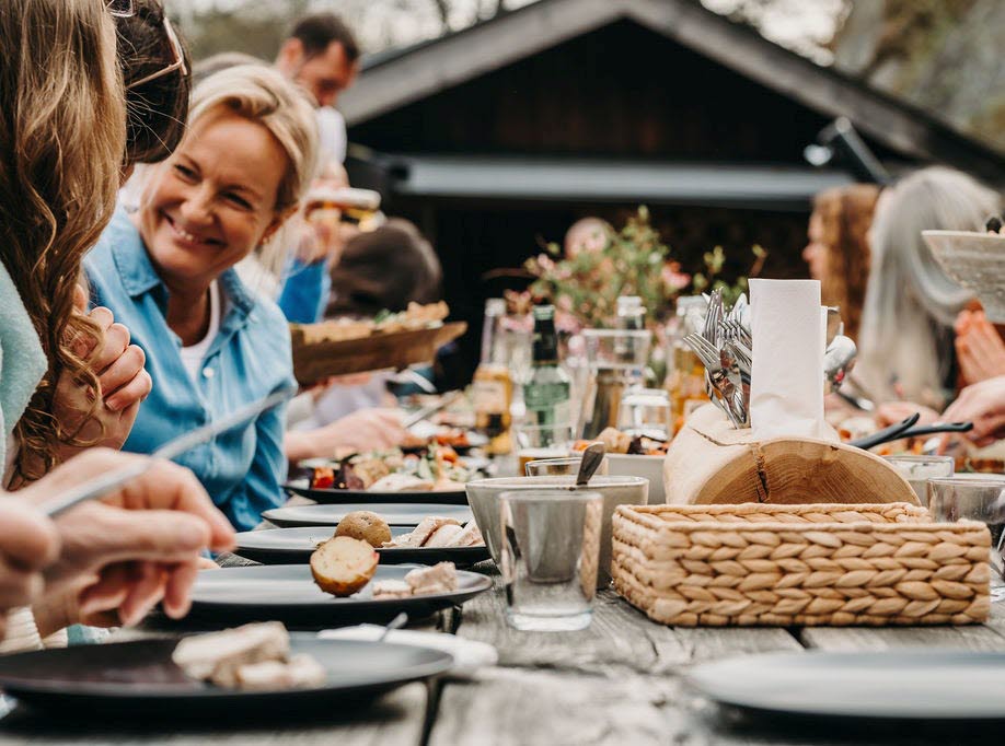 People eating at a large set table at Hällesdalen farm.