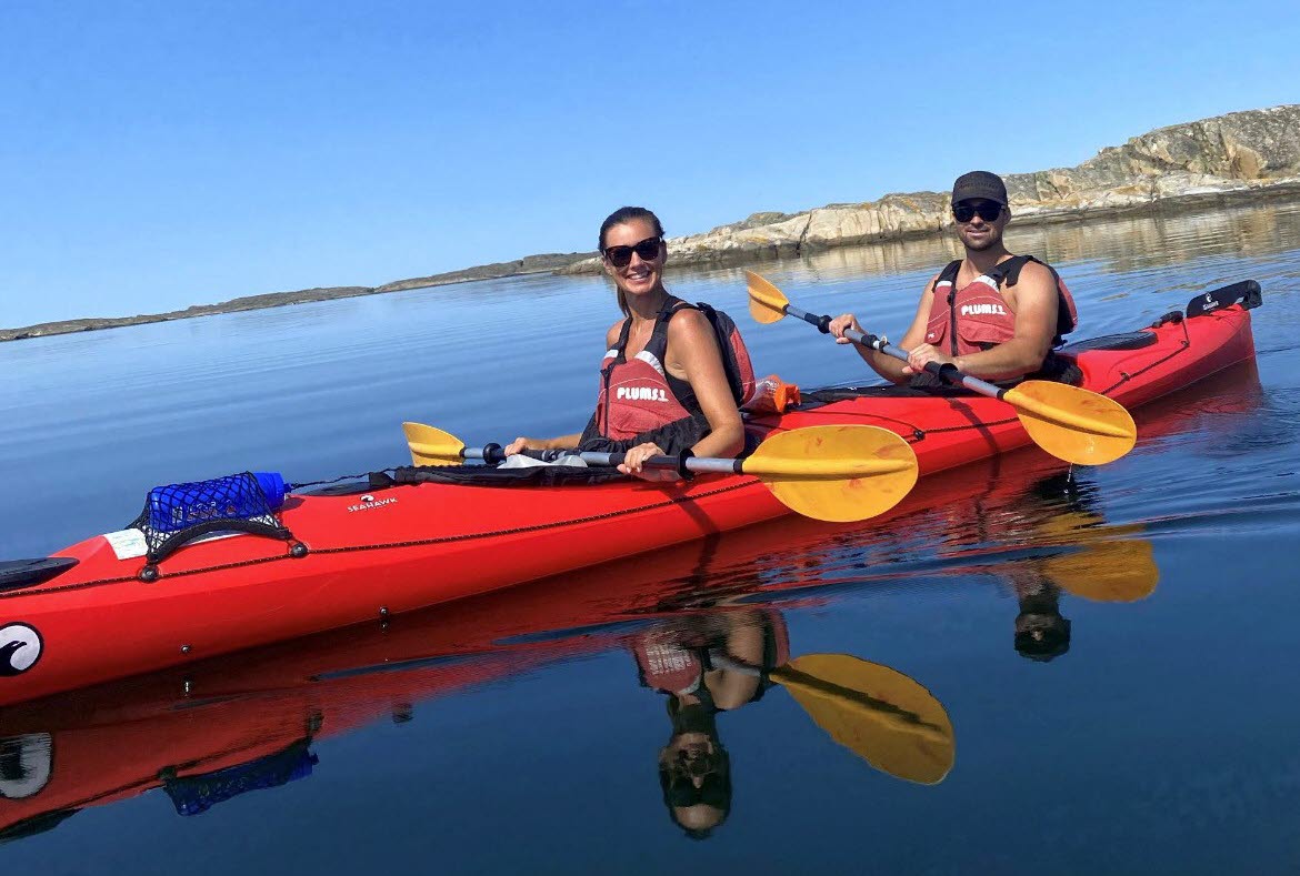 Kajakpaddlare på spegelblankt vatten en solig sommardag