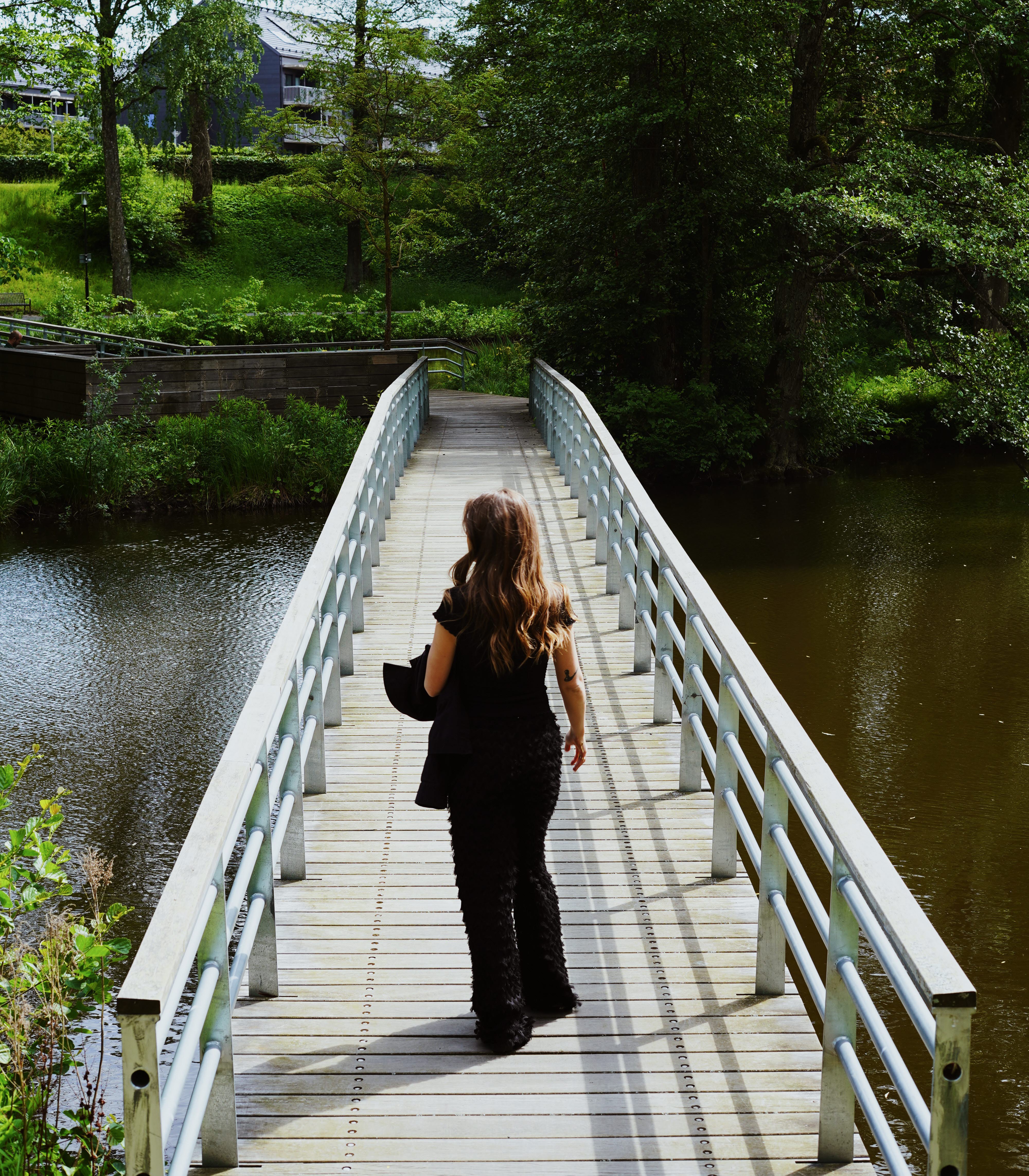 Kvinna promenerar på en träbro över ett vattendrag