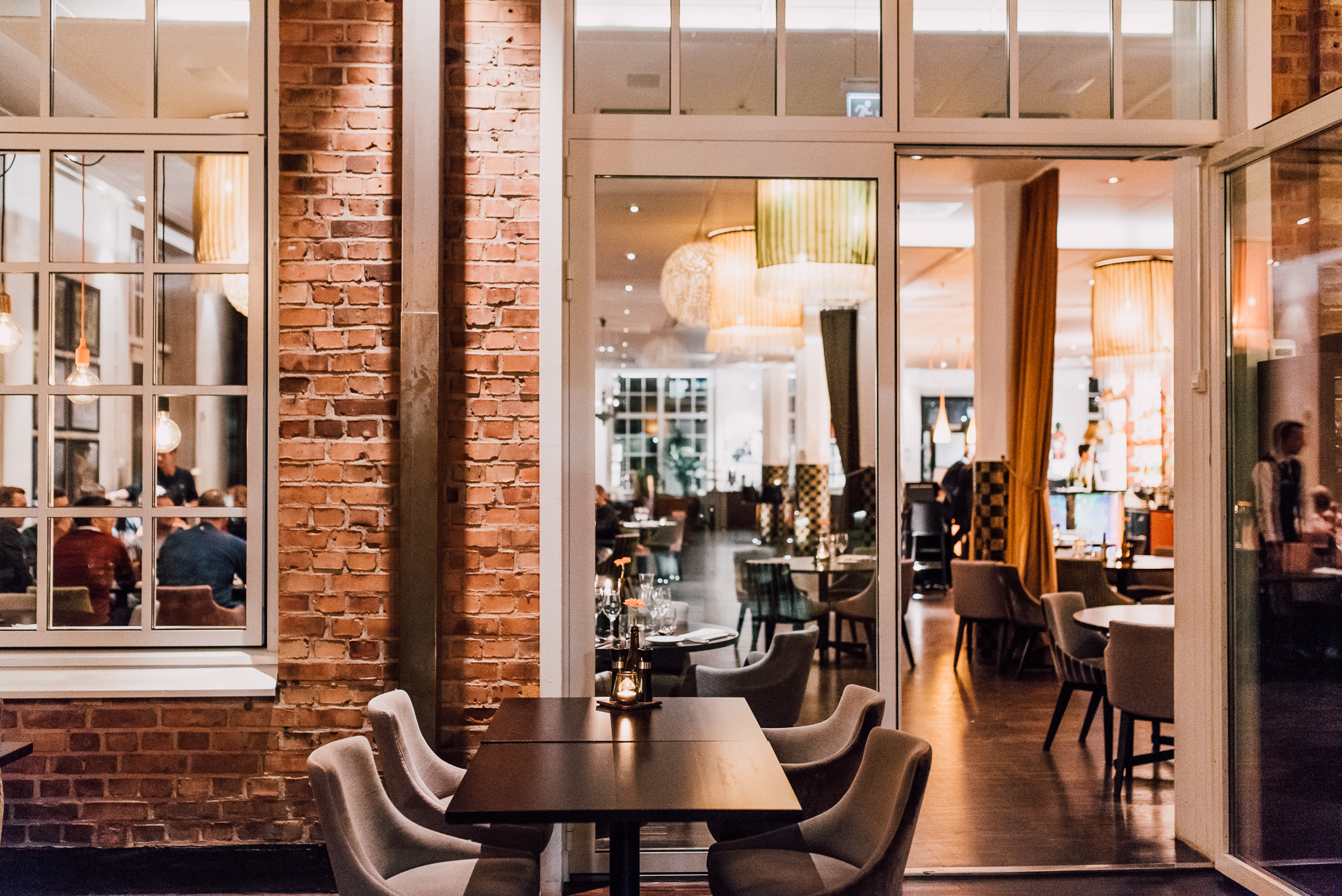 A nice and decorated dining room with brick walls and large windows.