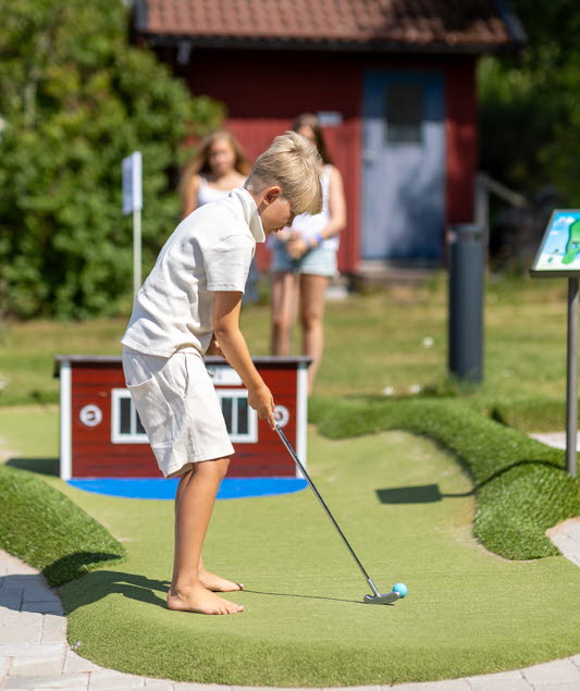 Pojke spelar minigolf på Lilla Brattön