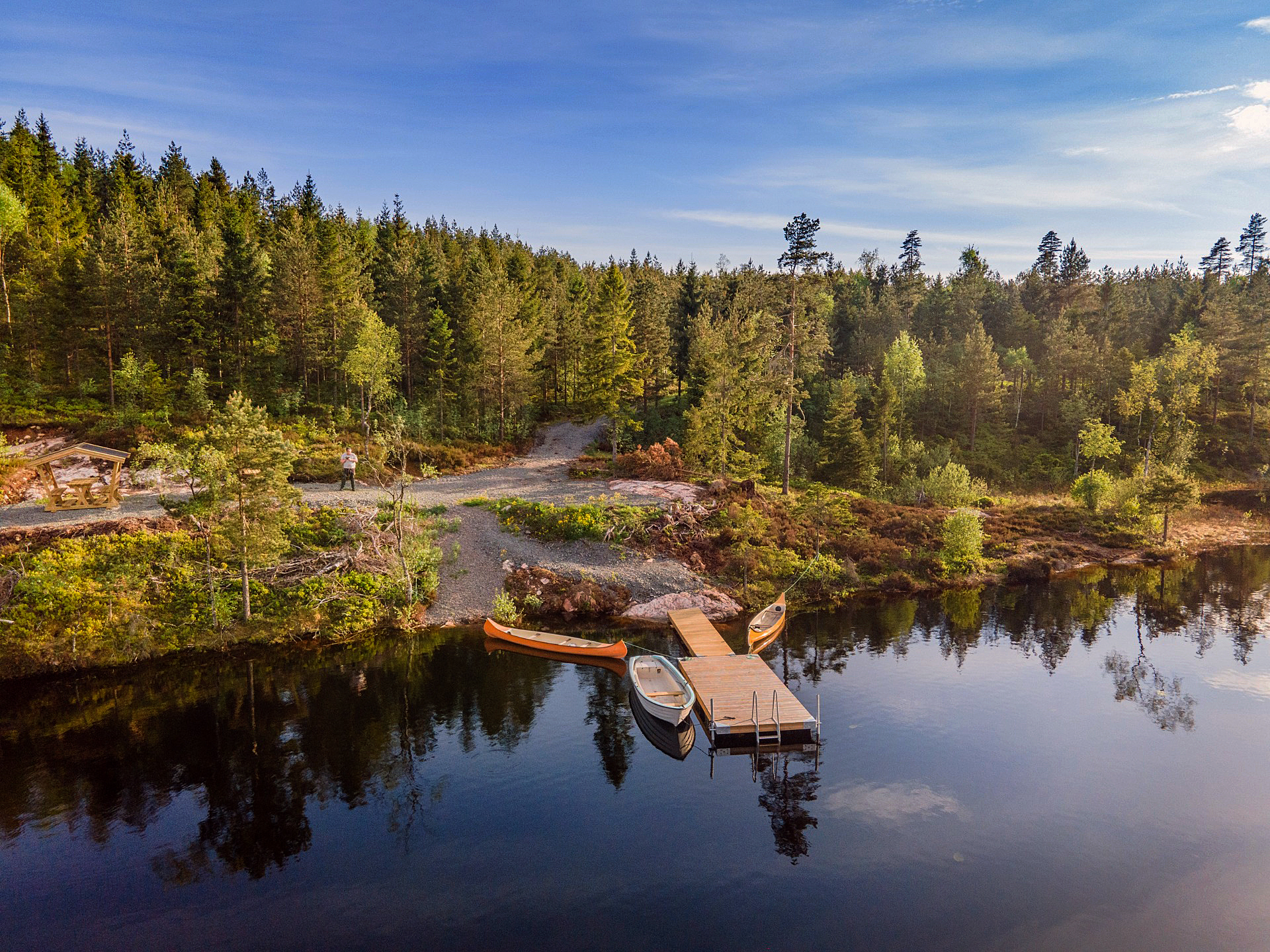 En vacker drönarbild över skog, klippa och två kanoter vid brygga i Lillsjön