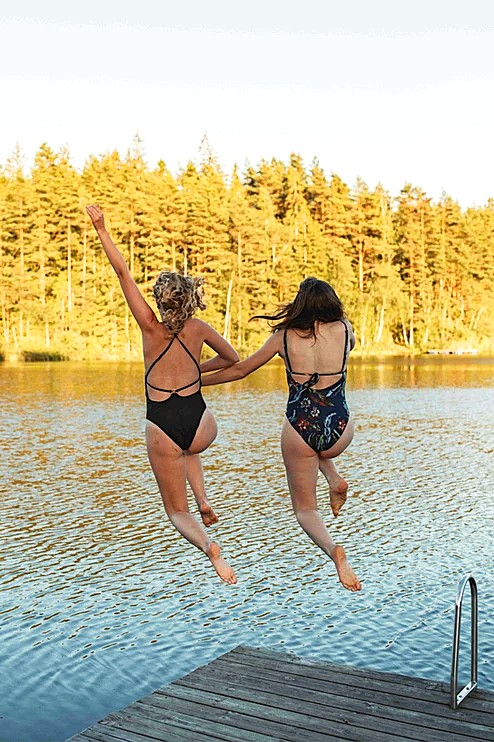 Två kvinnar hoppar från brygga i Gråbogårdens badsjö