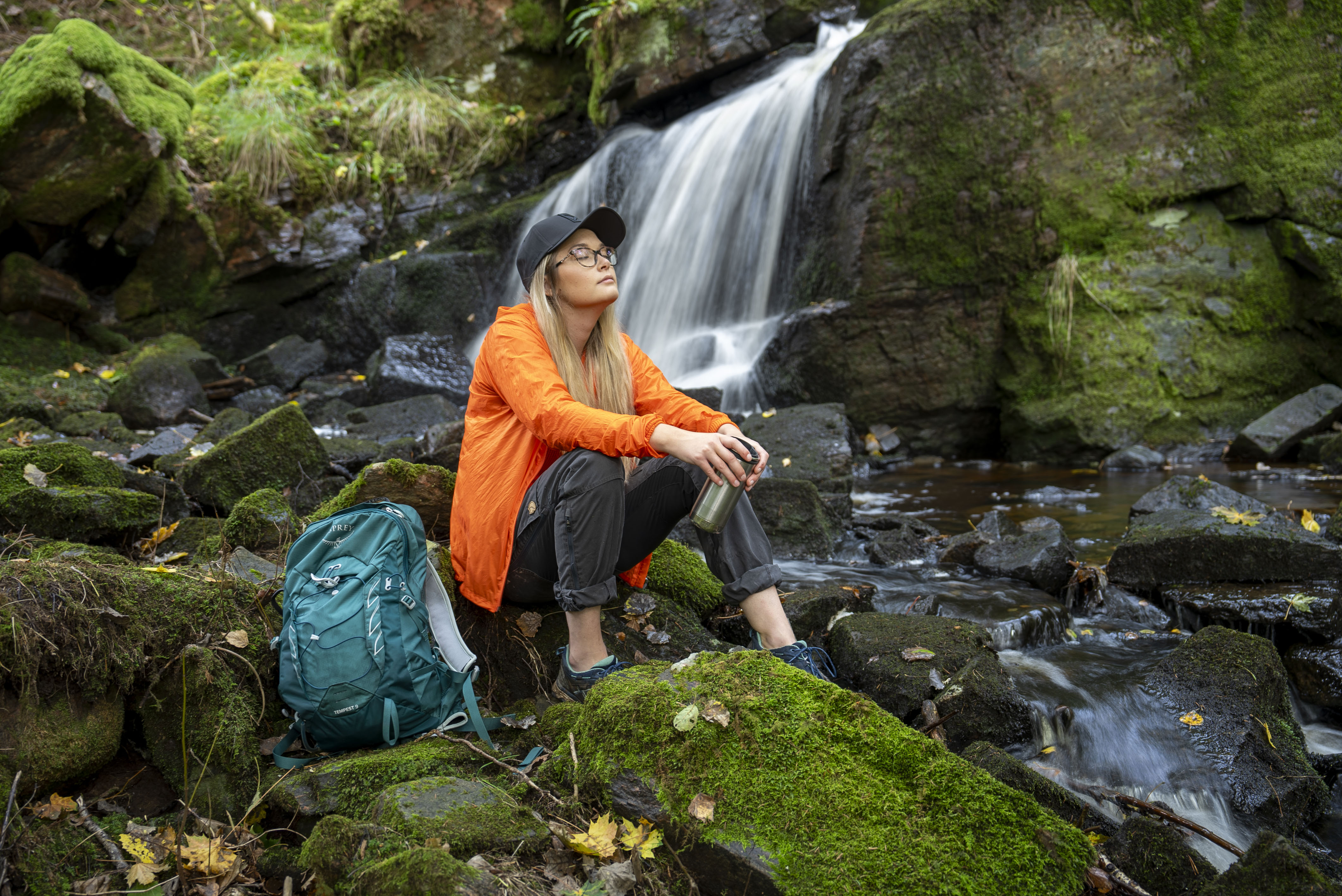 Vandrare med ryggsäck vilar vid forsande bäck, Café Torpet