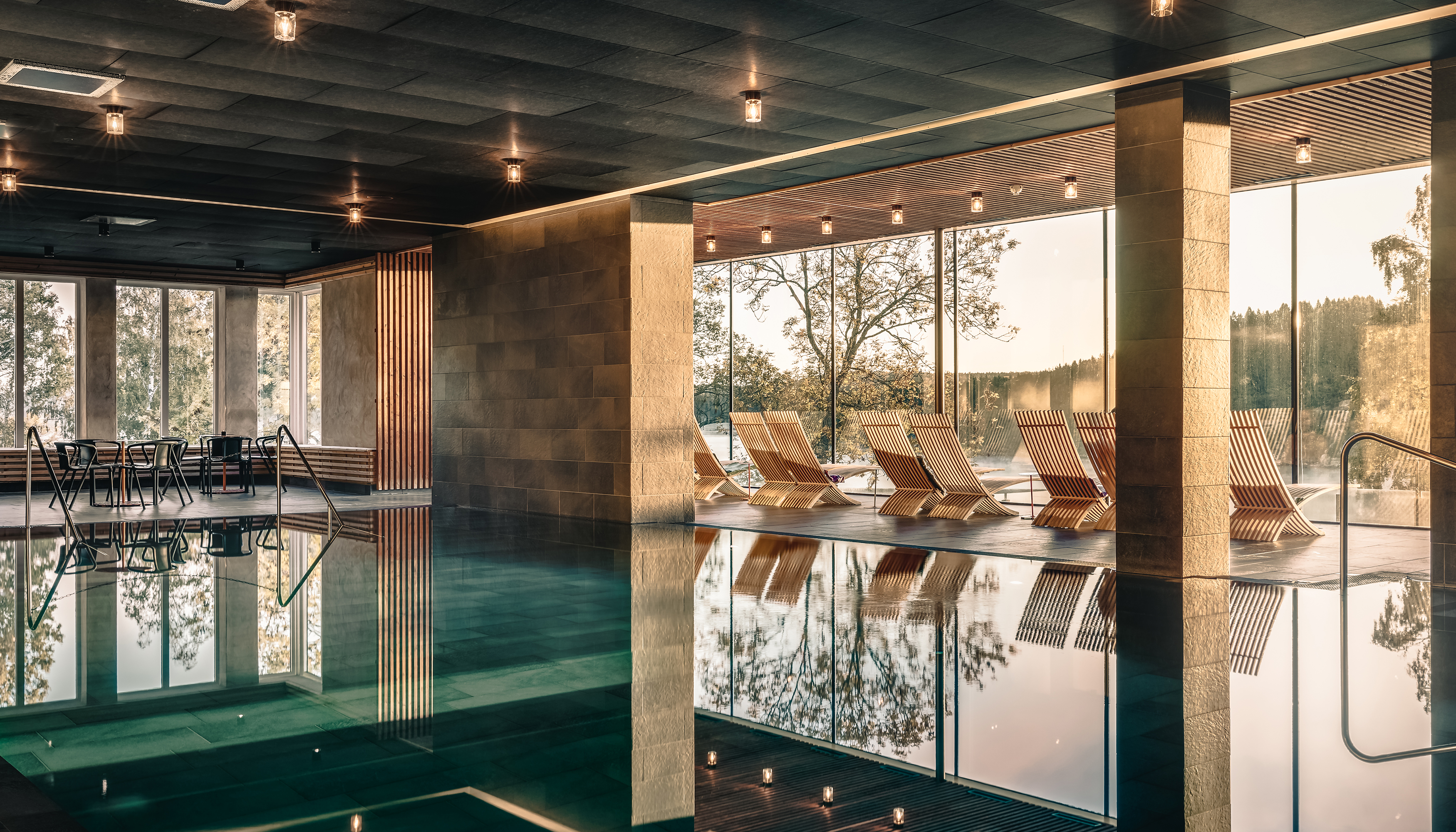 Large indoro pool with panorama windows and  relaxing chairs.