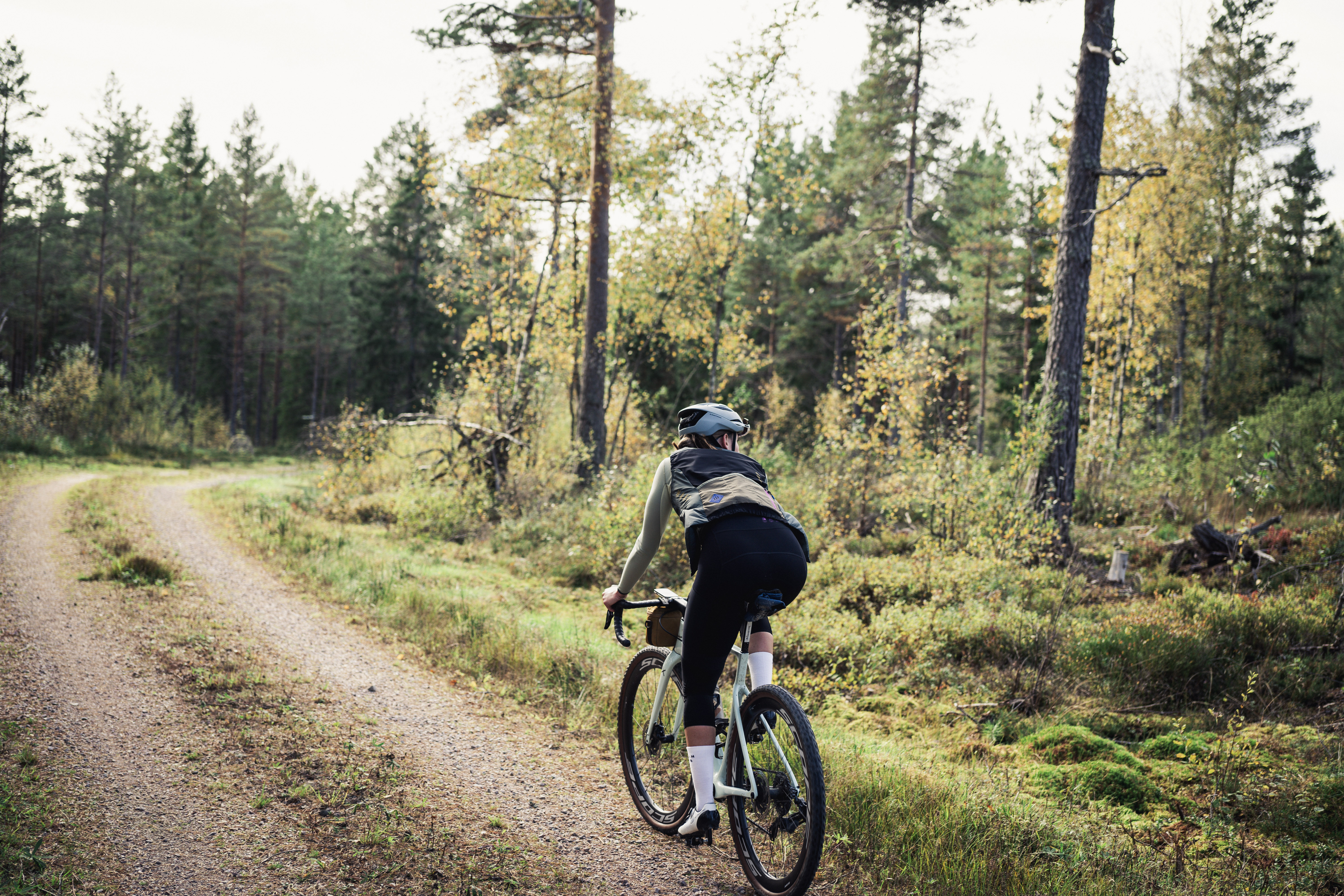 Cyclists on a dirt road in a working environment.