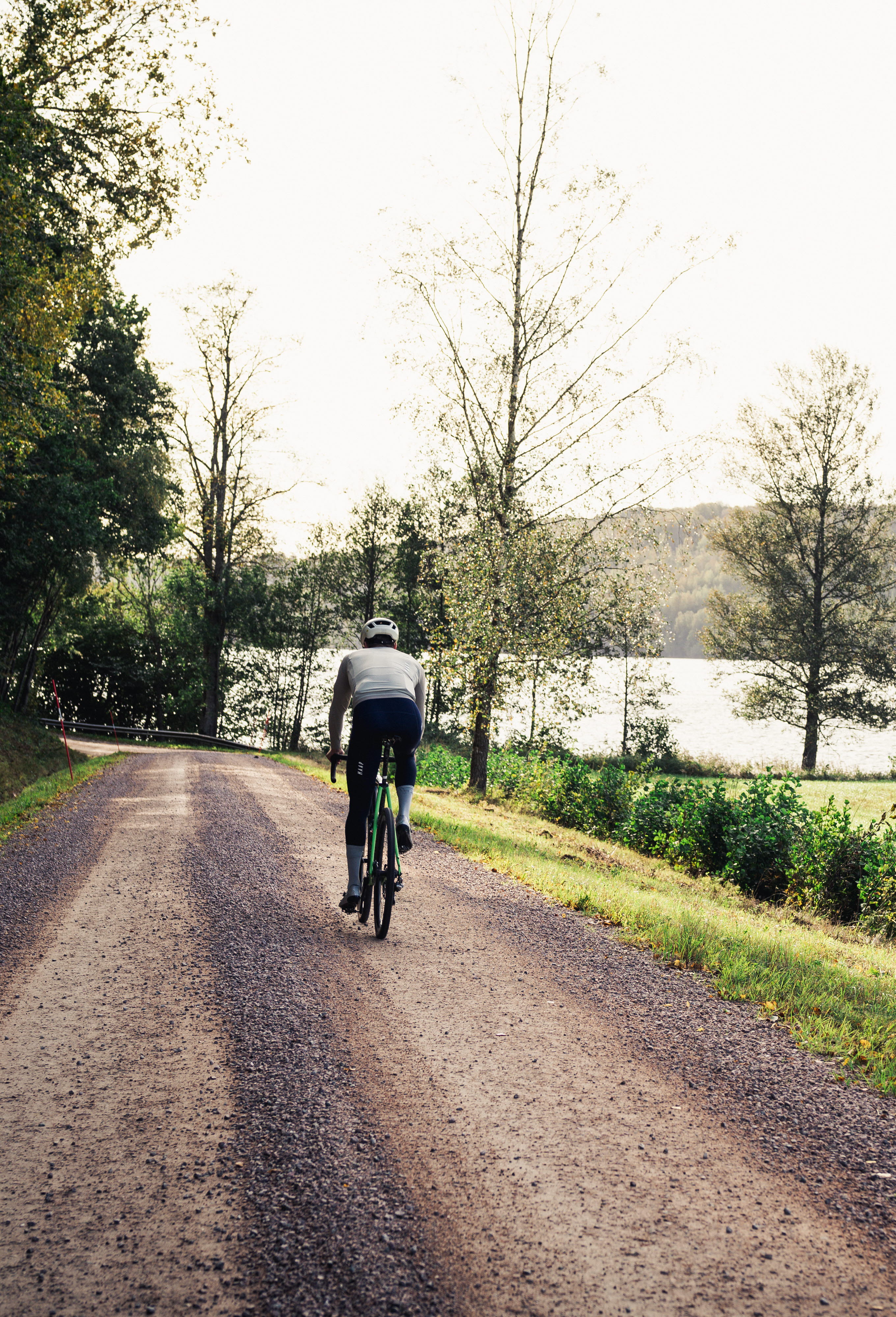 Cyklist på en grusväg i bruksmiljö.