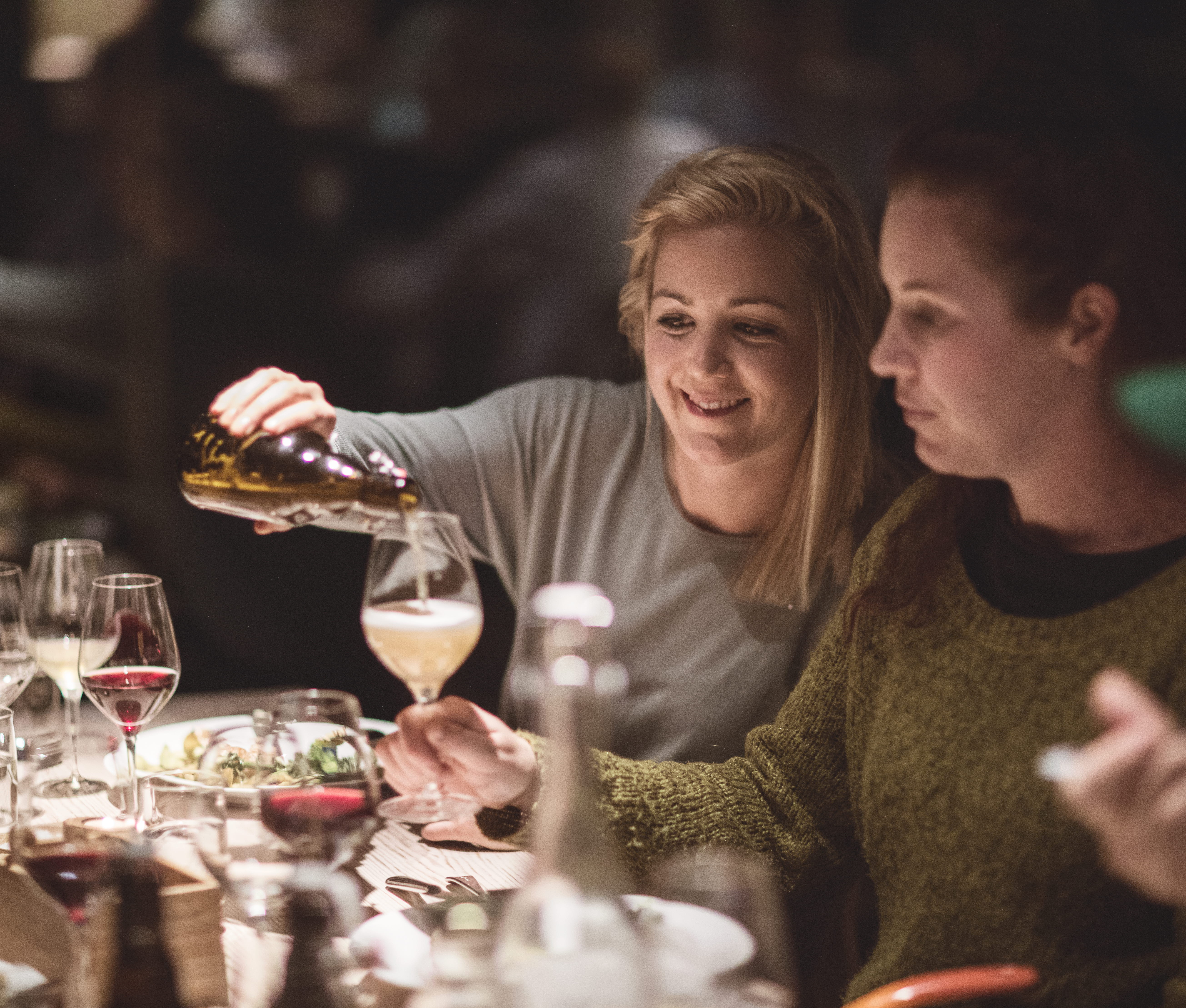 Kvinna fyller ett glas vid ett dukat bord