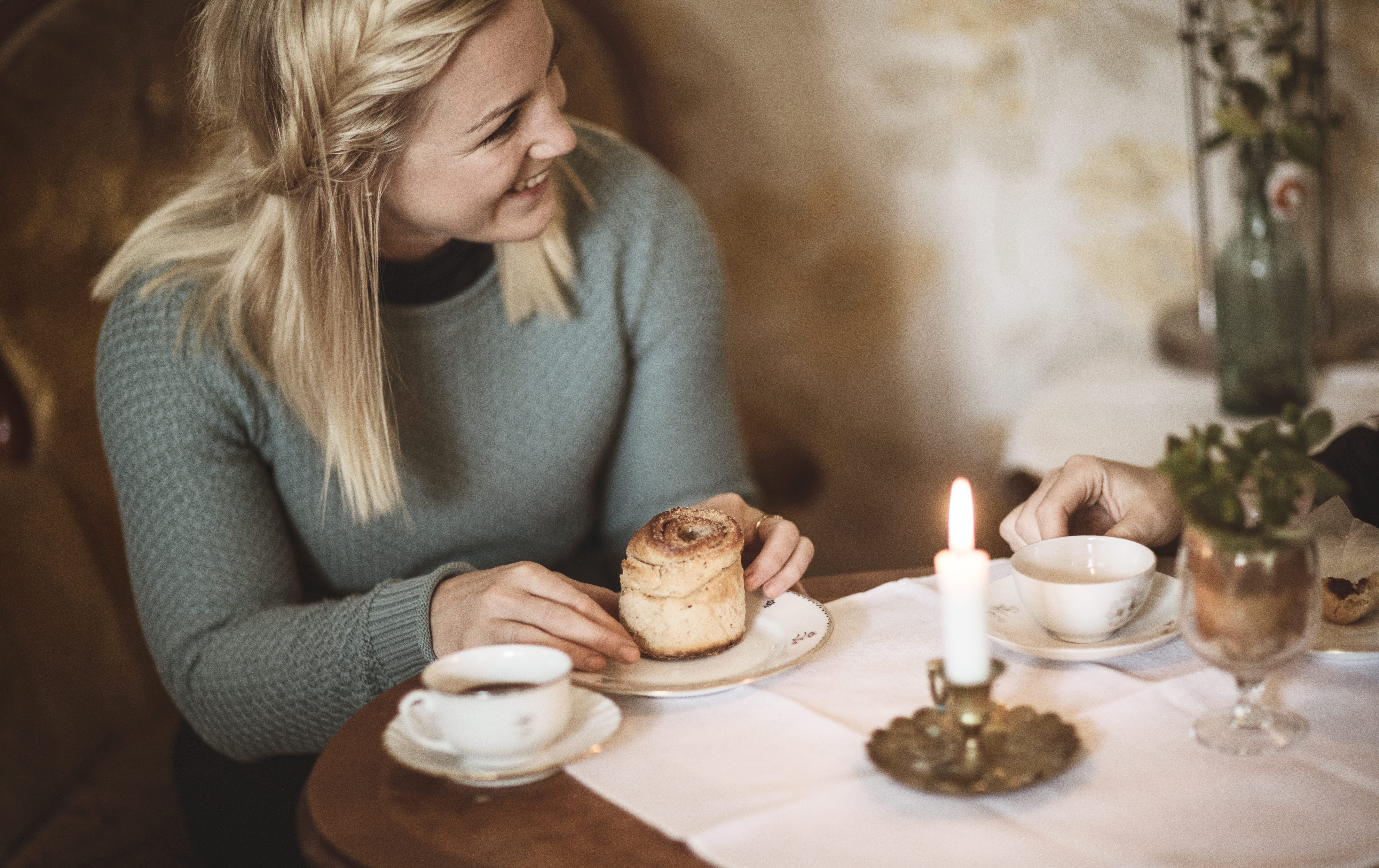 Kvinna fikar på kanelbulle och kaffe