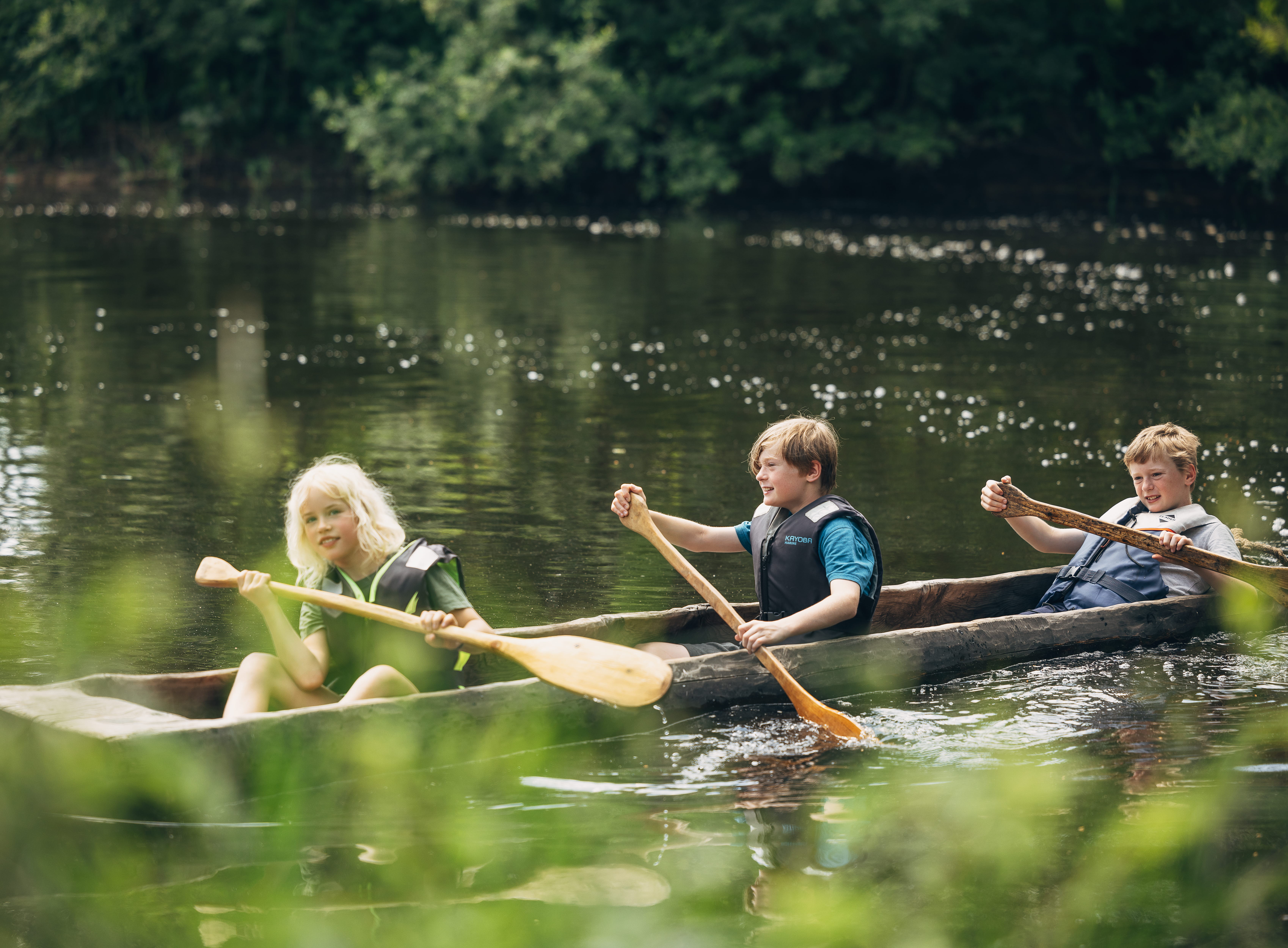Barn sitter i en kanot och paddlar.