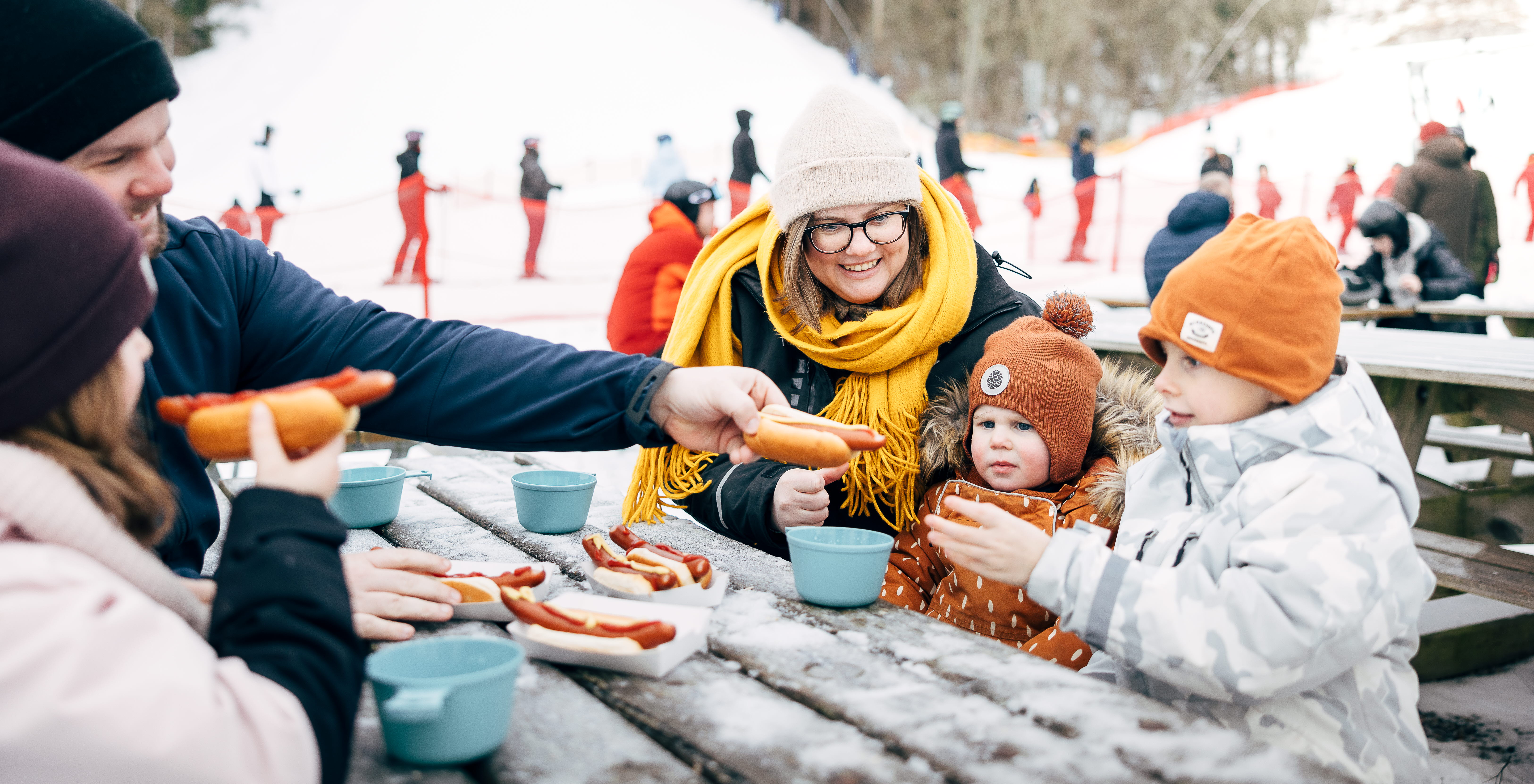 Familj tar en paus från skidåkning och äter en måltid.