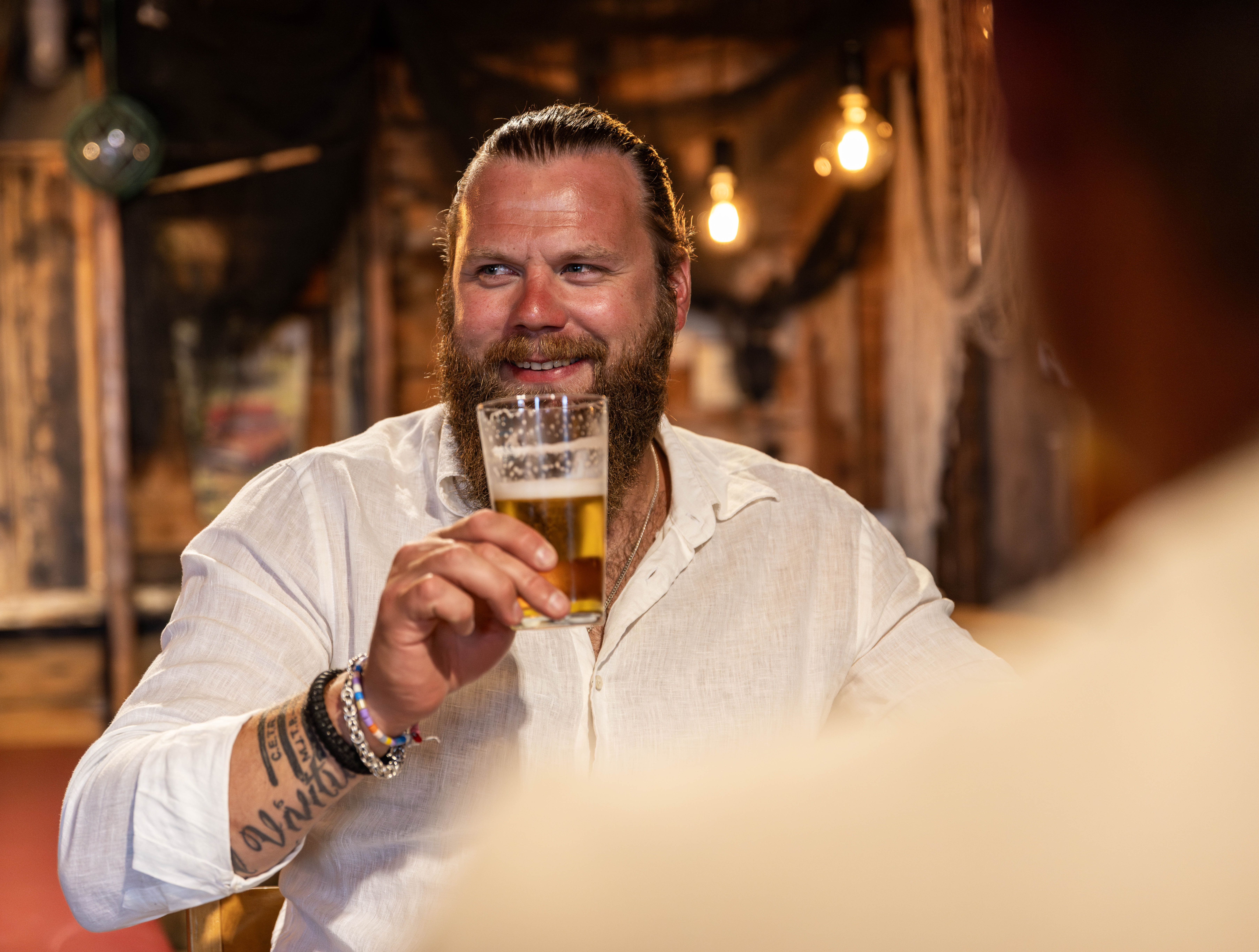 A man is sitting in a restaurant drinking a beer.