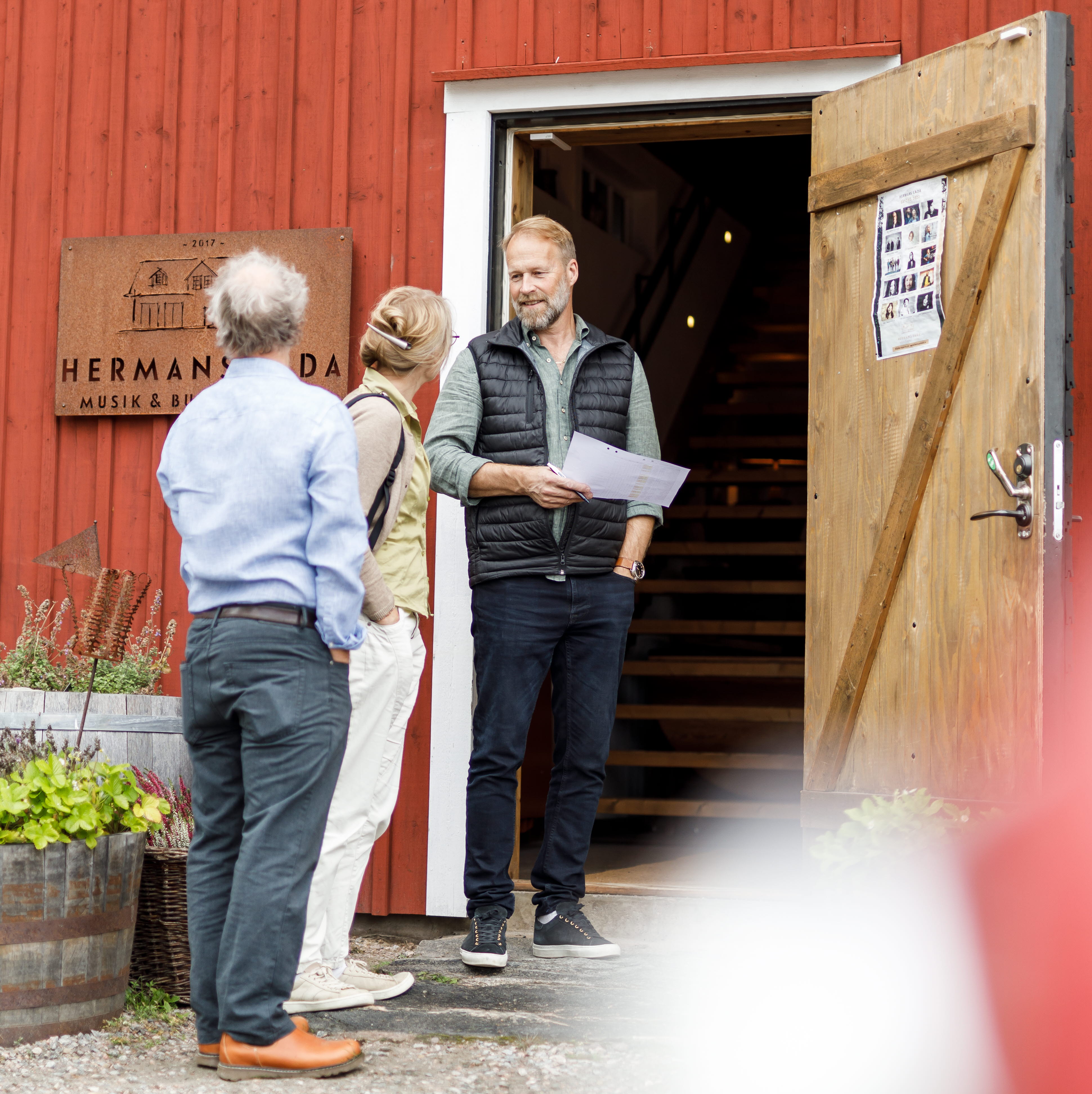 En man tar emot ett sällskap vid ingången till Hermans Lada.