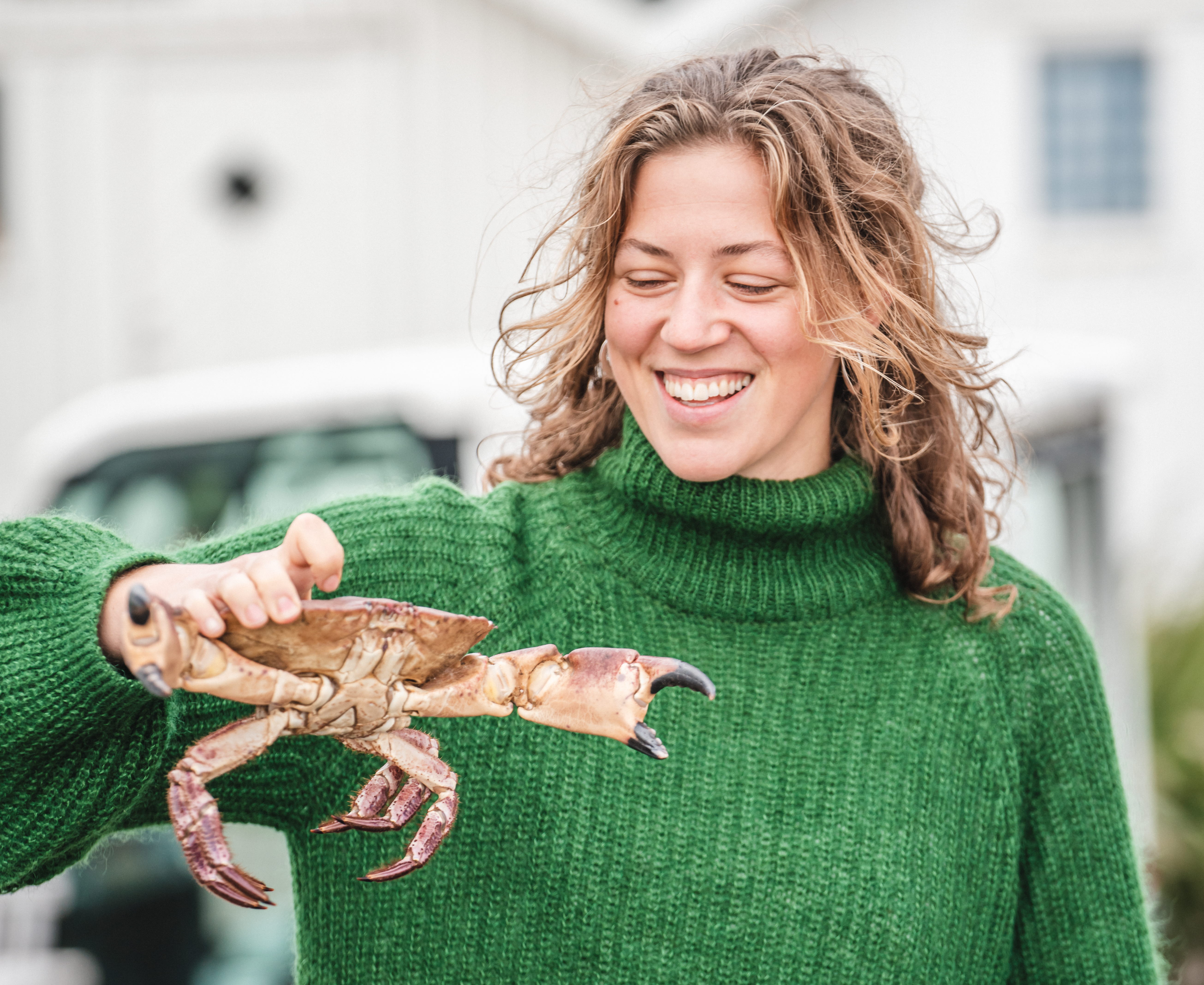 Kvinna håller en krabba utanför Kajkanten Vrångö
