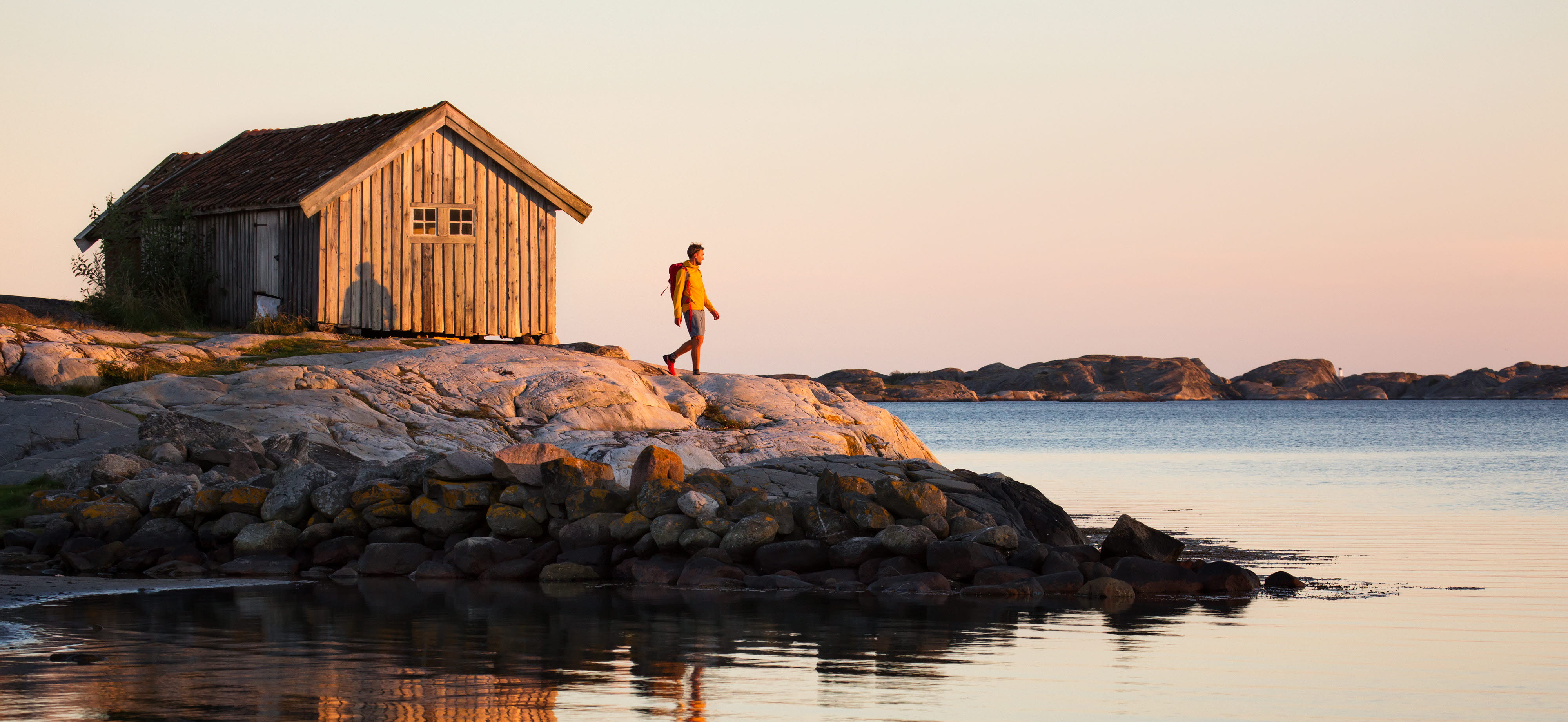 Vandrande man vid sjöbod i solnedgången