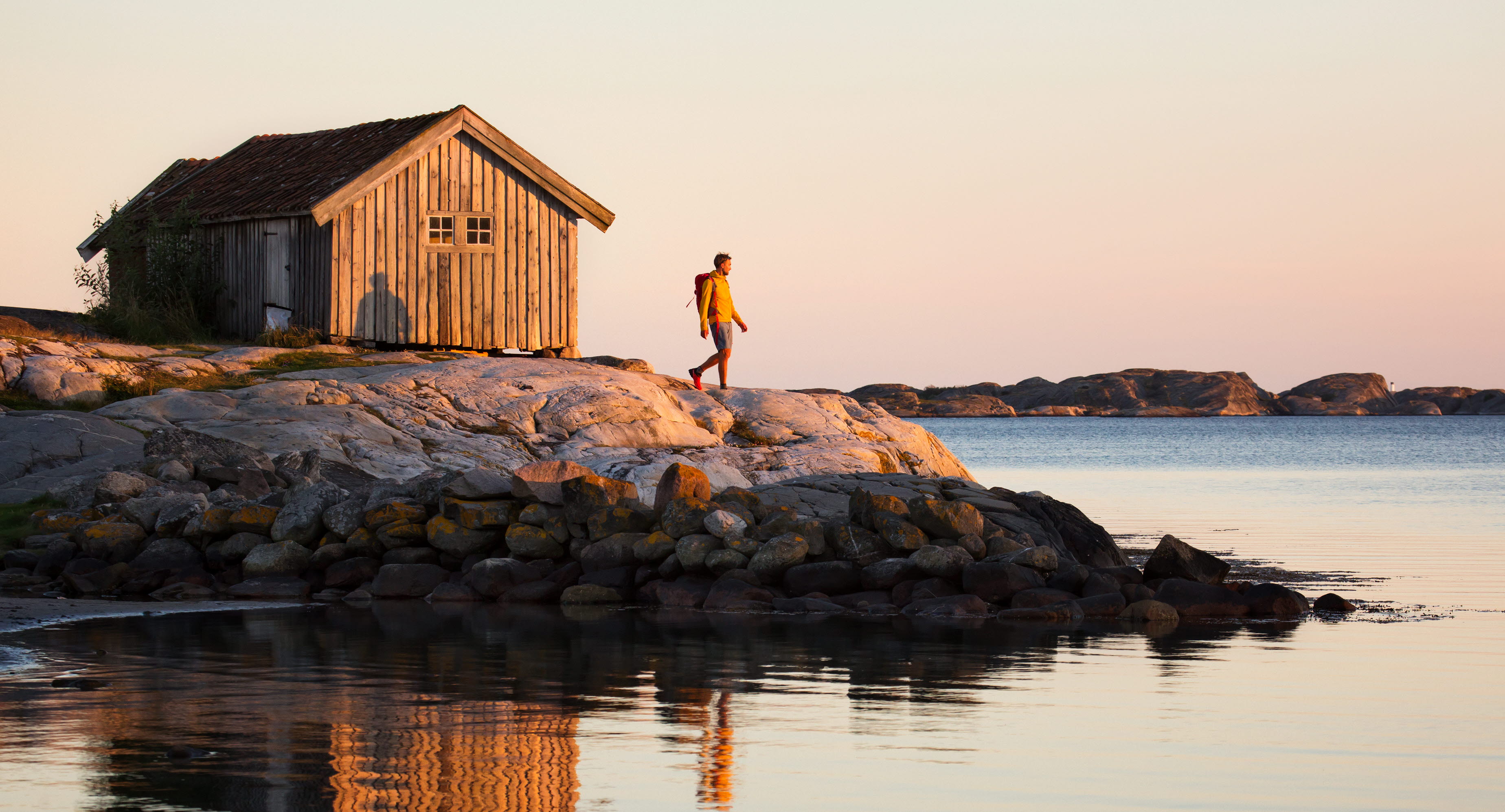 Vandrande man vid sjöbod i solnedgången