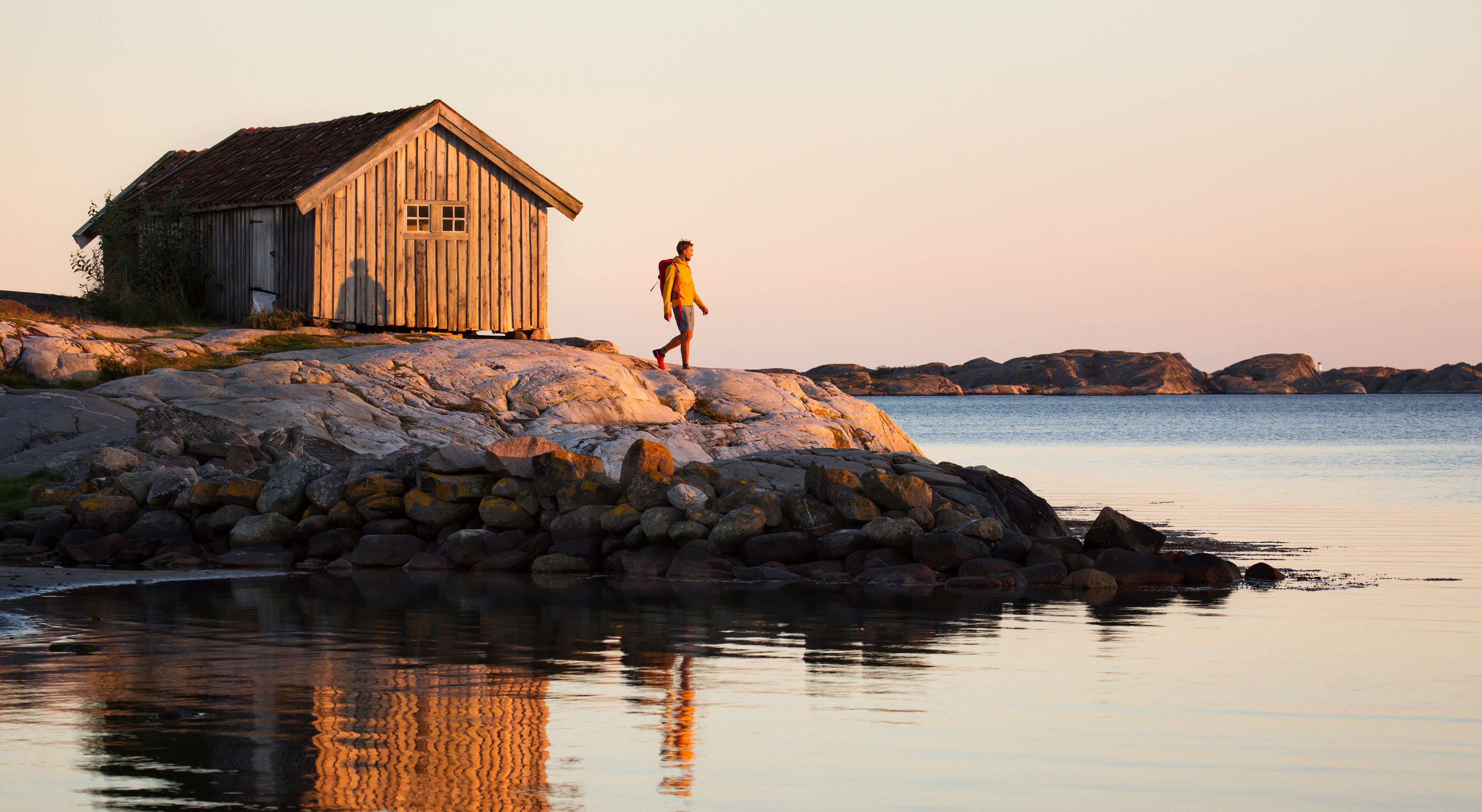 Vandrande man vid sjöbod i solnedgången