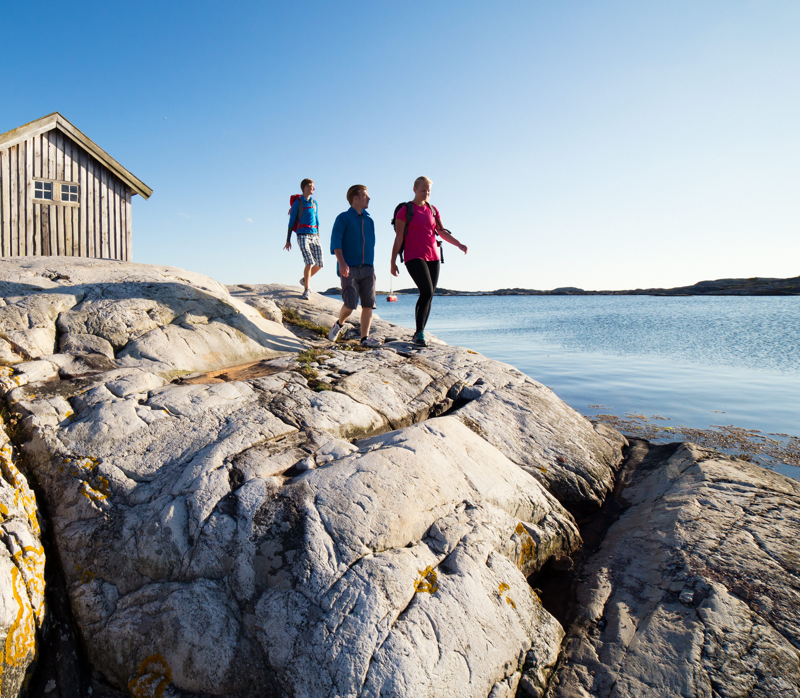 Sällskap vandrar på klipporna vid sjöbod