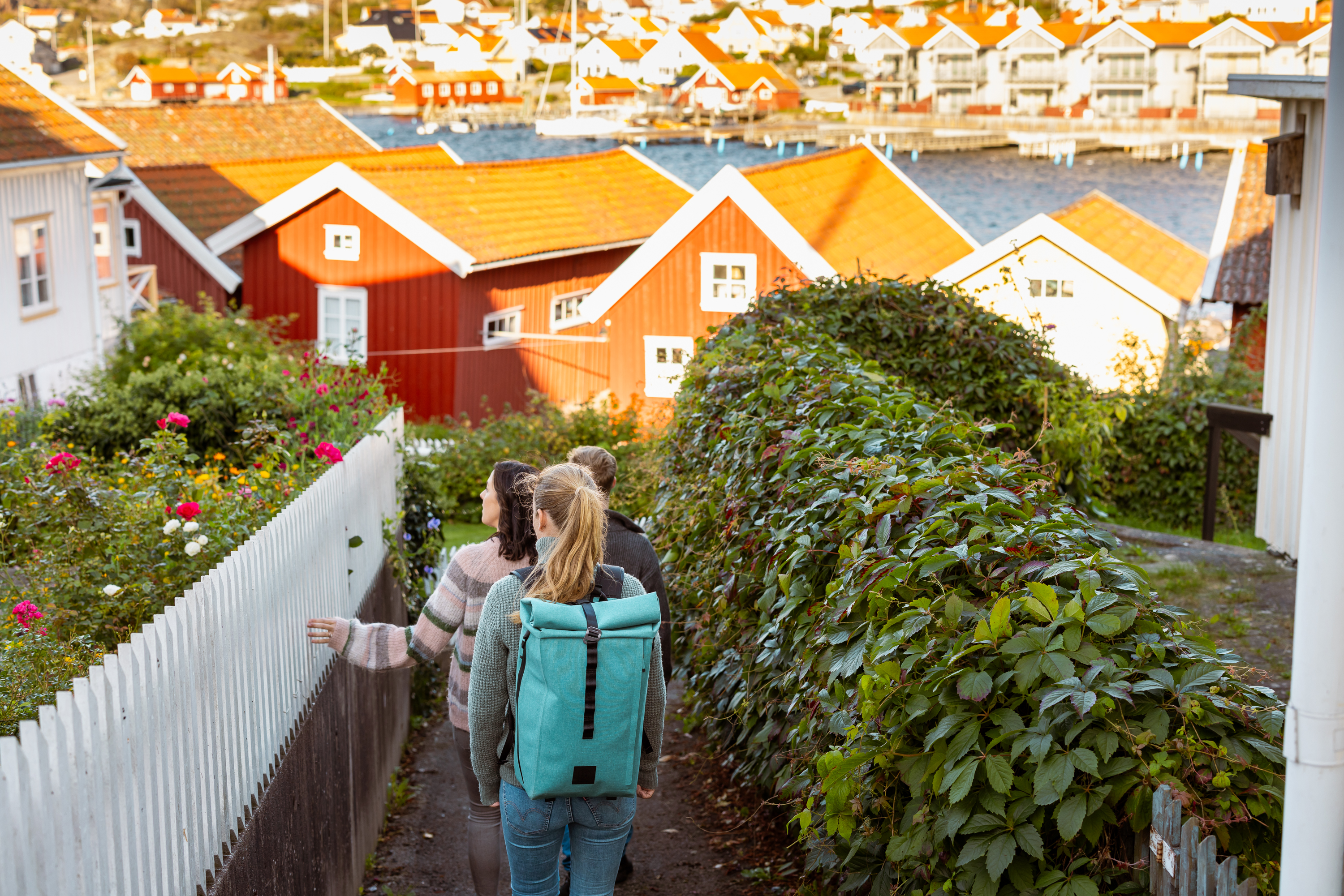 Three people are walking among boat houses.