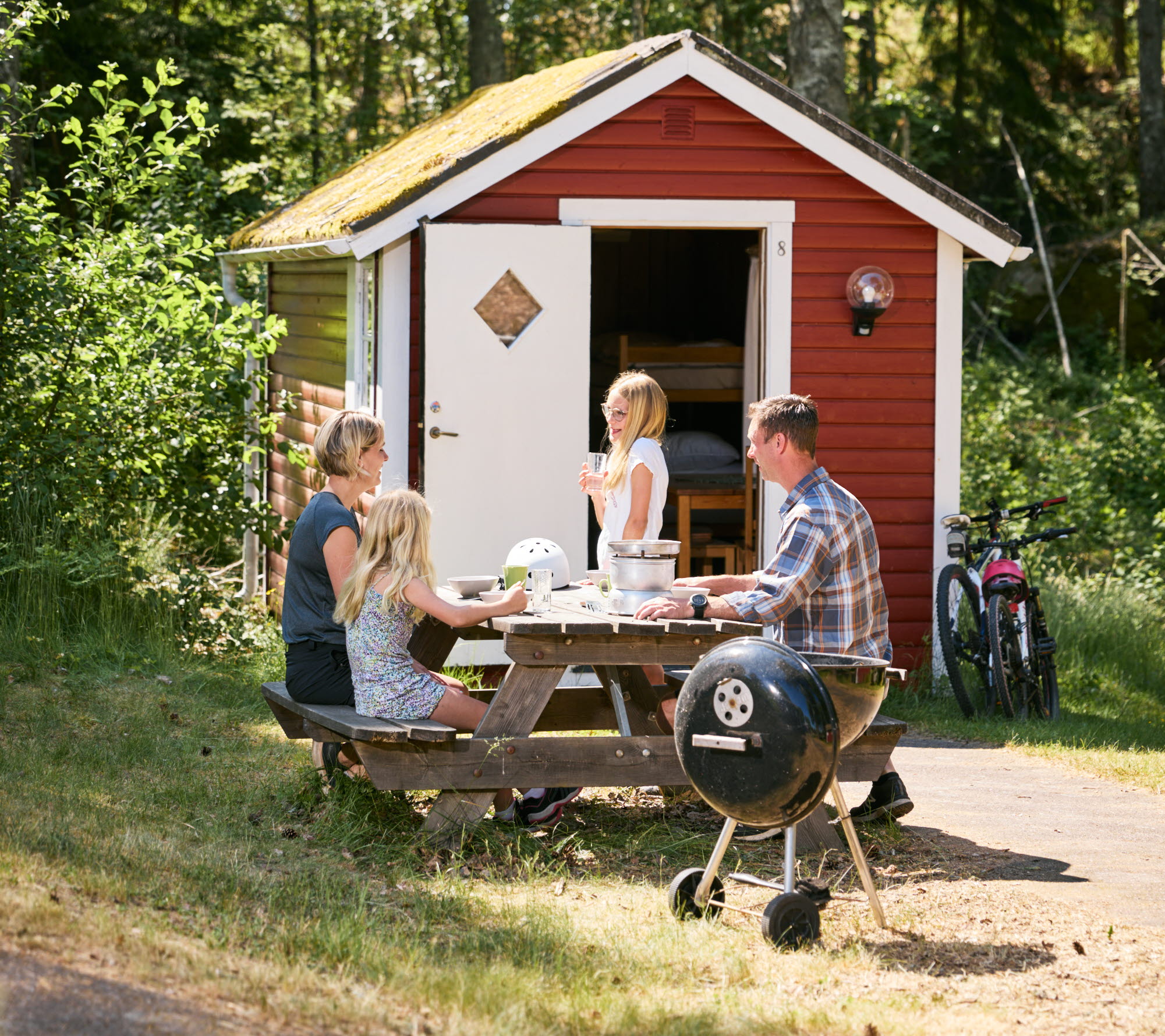 Familj vid en campingstuga.