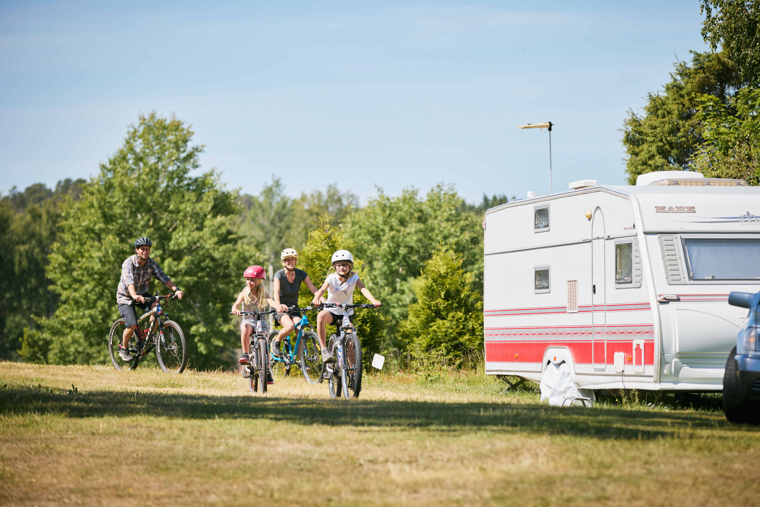 Familj cyklar tillsammans på en camping.