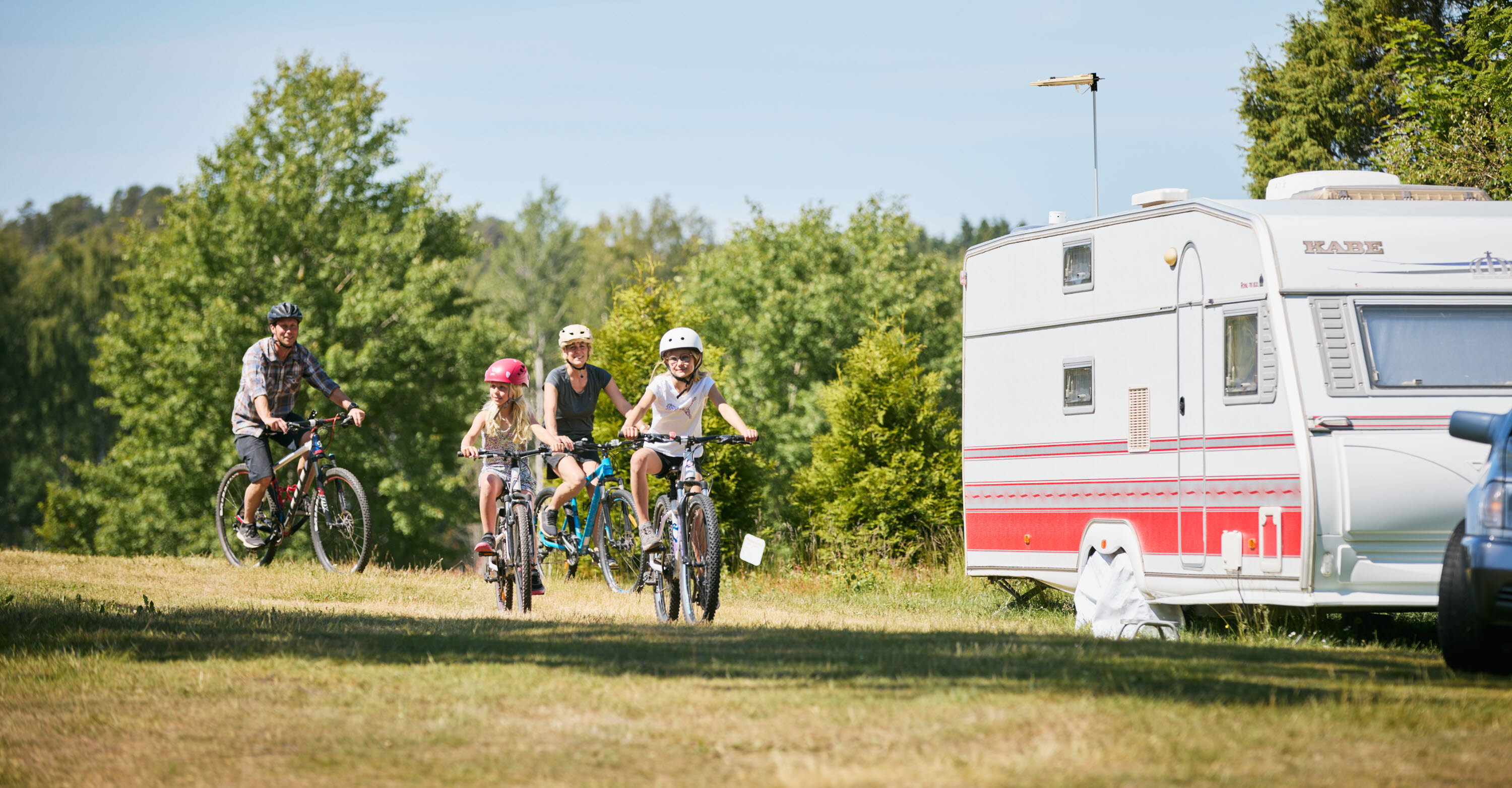 Familj cyklar tillsammans på en camping.