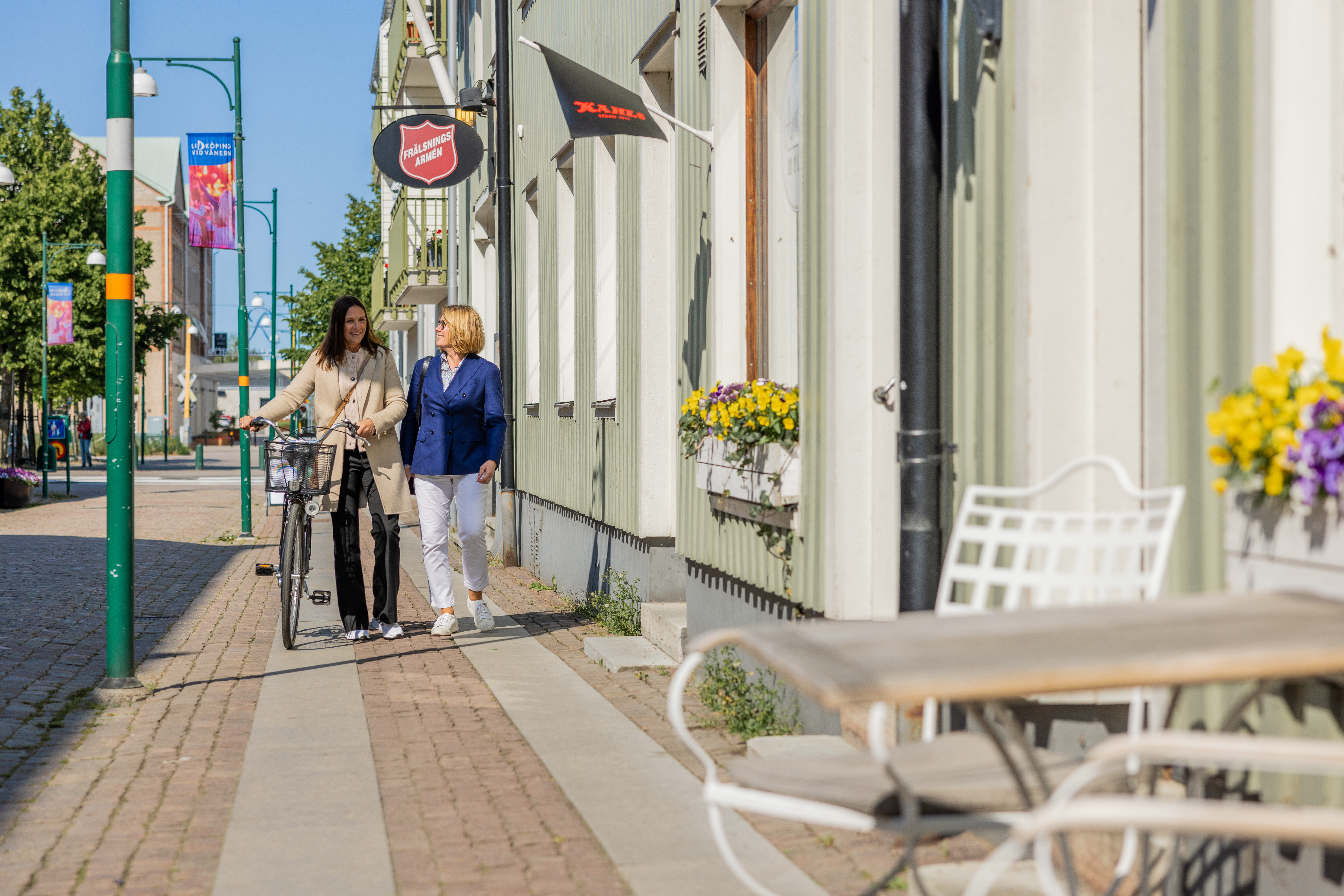 Två kvinnor promenerar i en småstad.