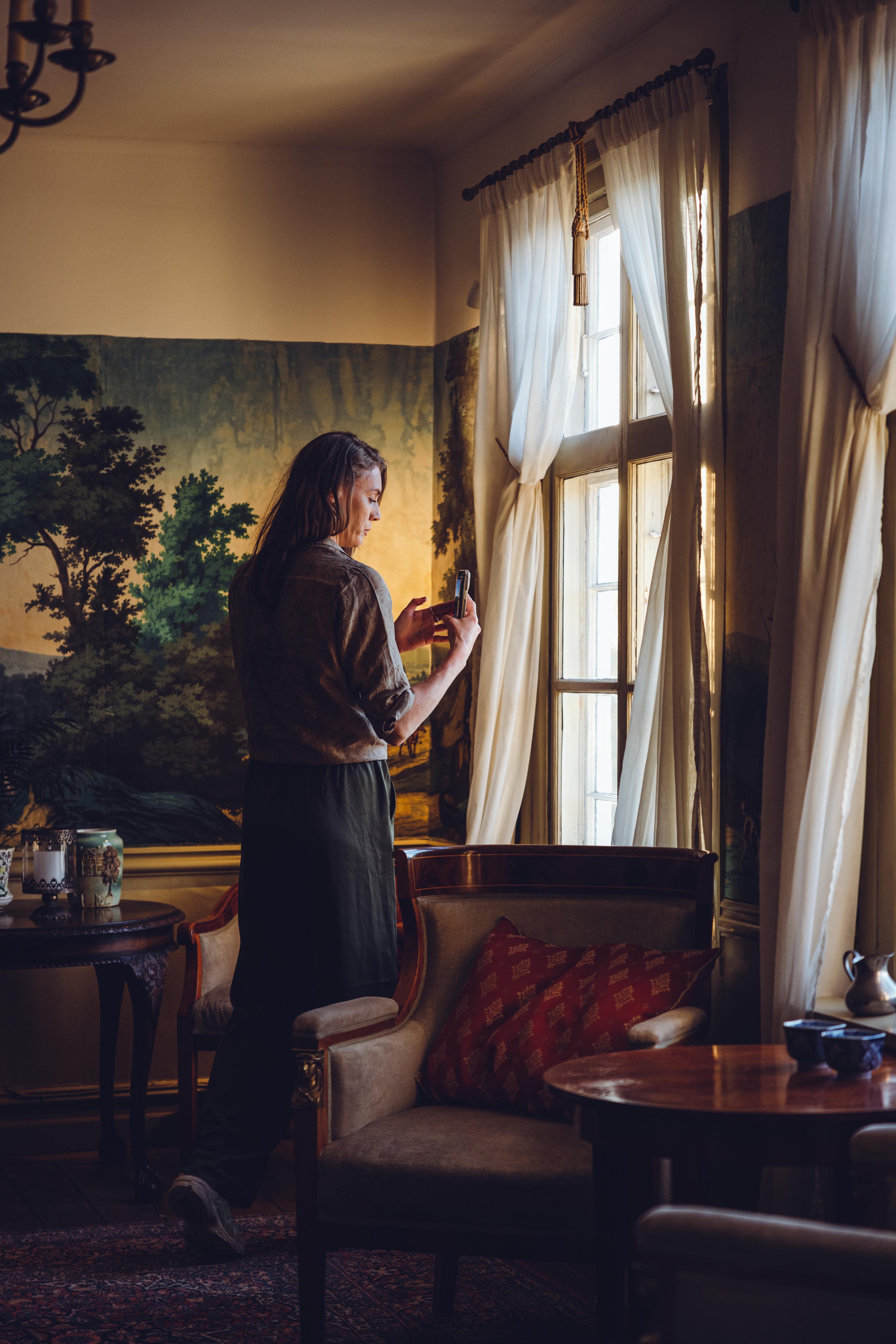 A woman at Tofta Herrgård takes a picture with her phone.