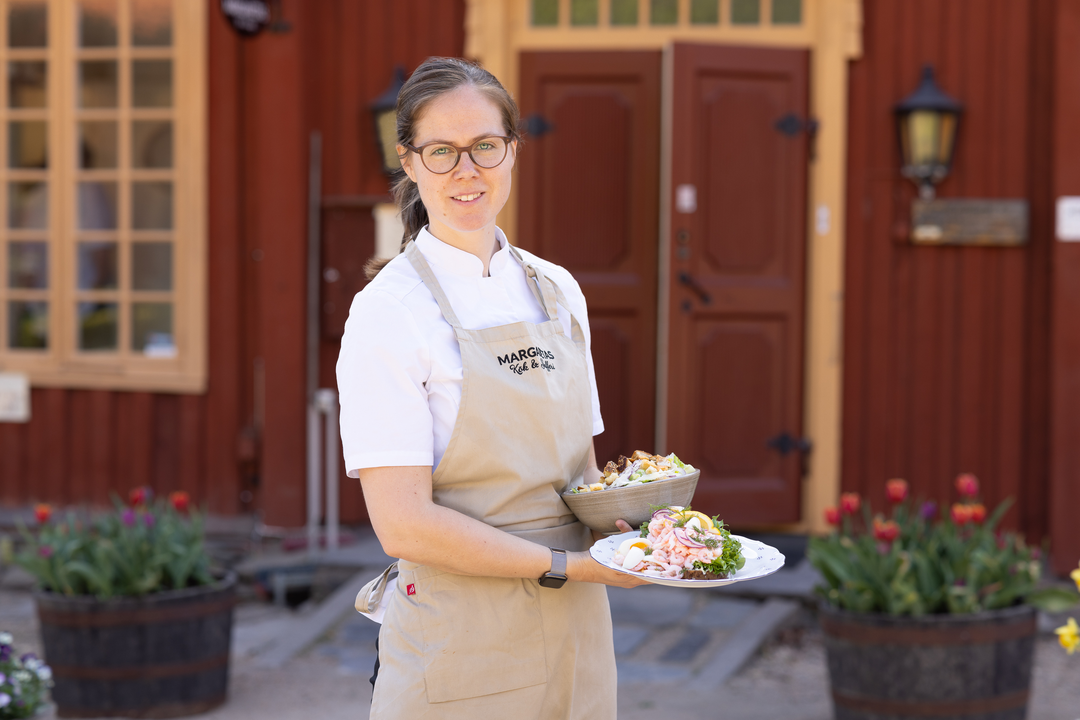 Kvinna håller i tallrikar hos Margaretas kök och skafferi