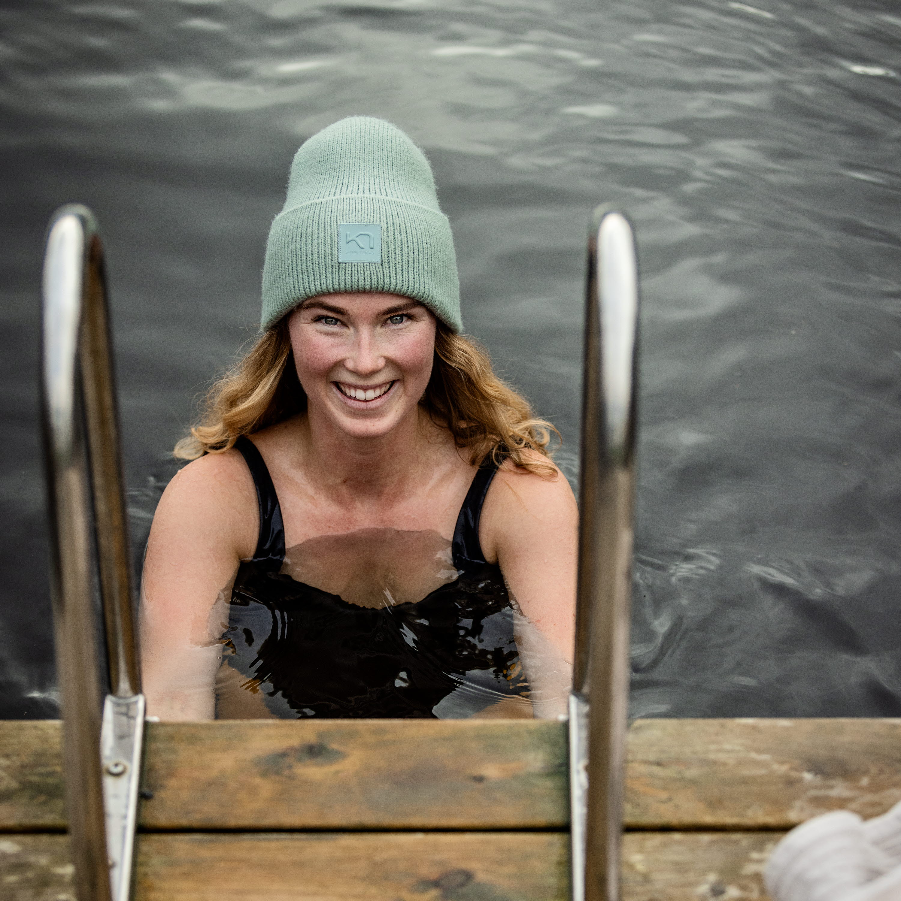 Kvinna med mössa som tar ett dopp i en sjö.