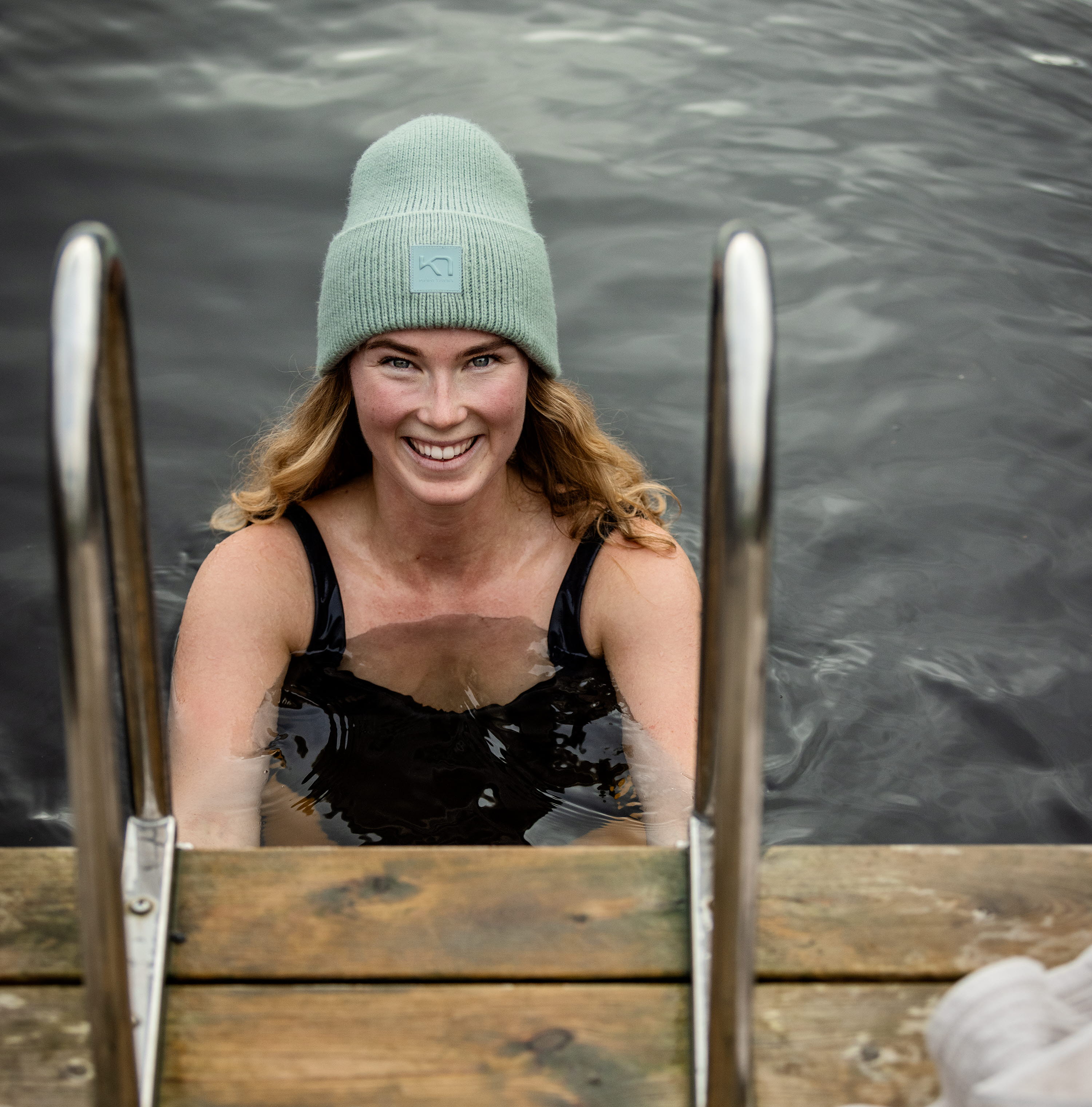 Kvinna med mössa som tar ett dopp i en sjö.