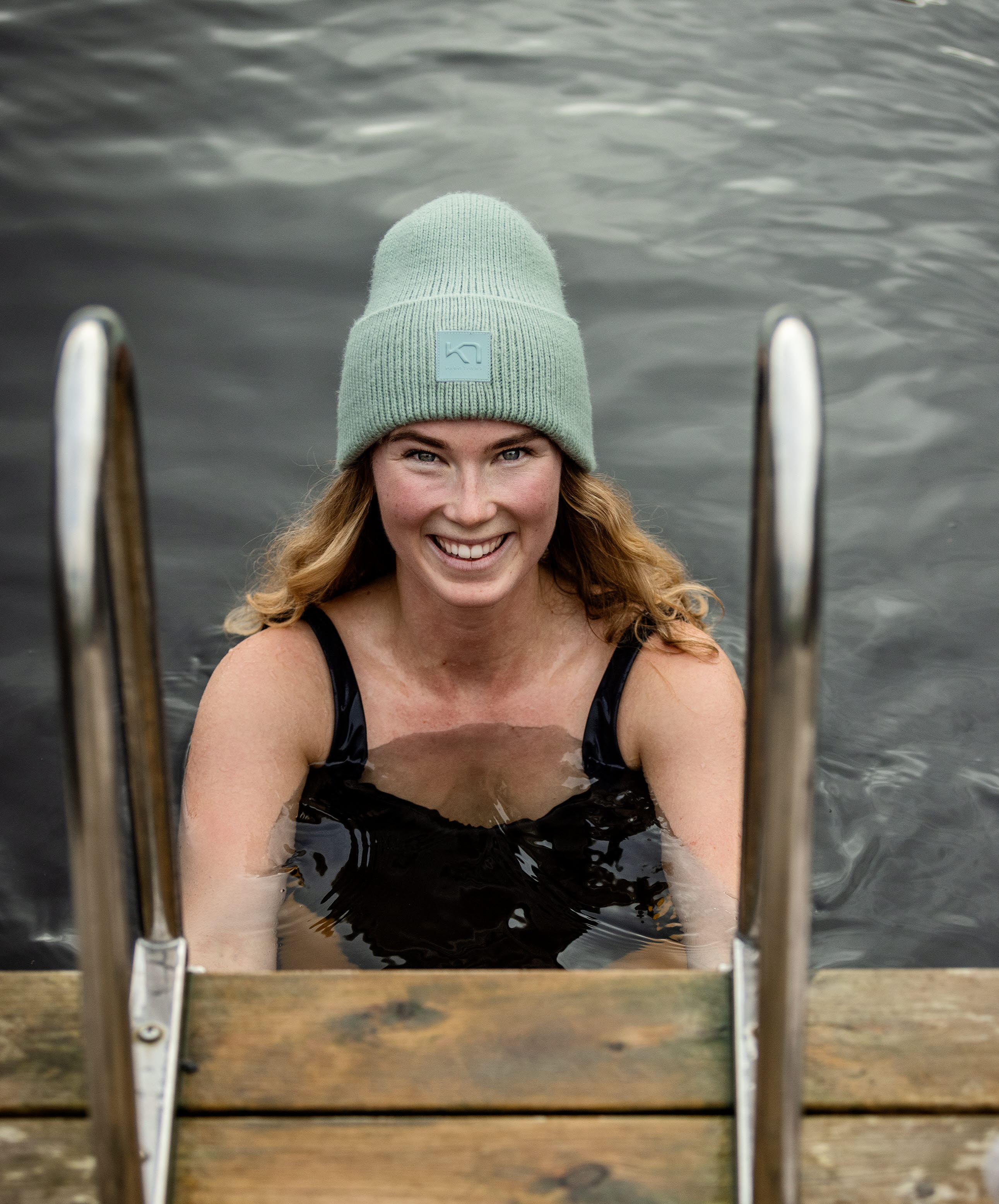 Kvinna med mössa som tar ett dopp i en sjö.