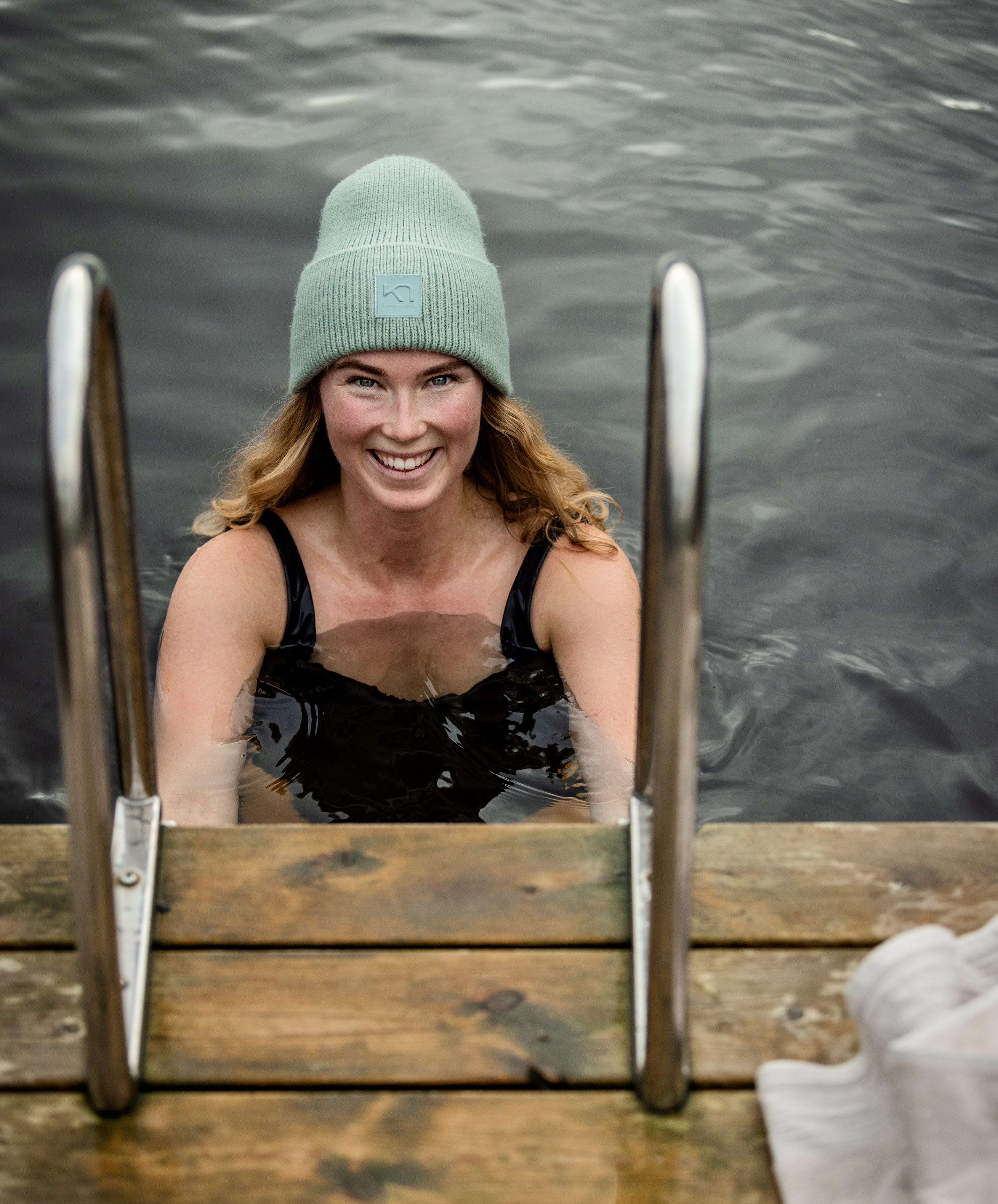 Kvinna med mössa som tar ett dopp i en sjö.