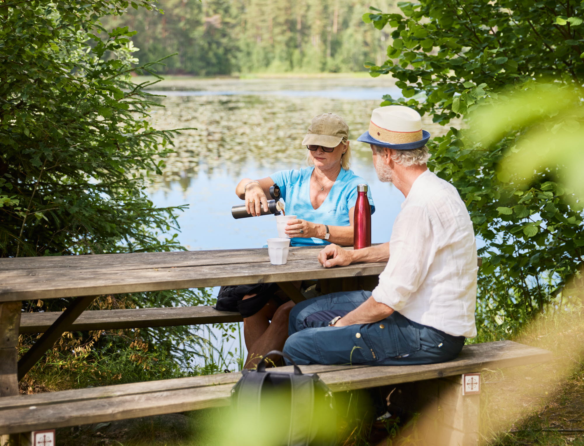 Två personer som vandrar på pilgrimsled genom skogen.