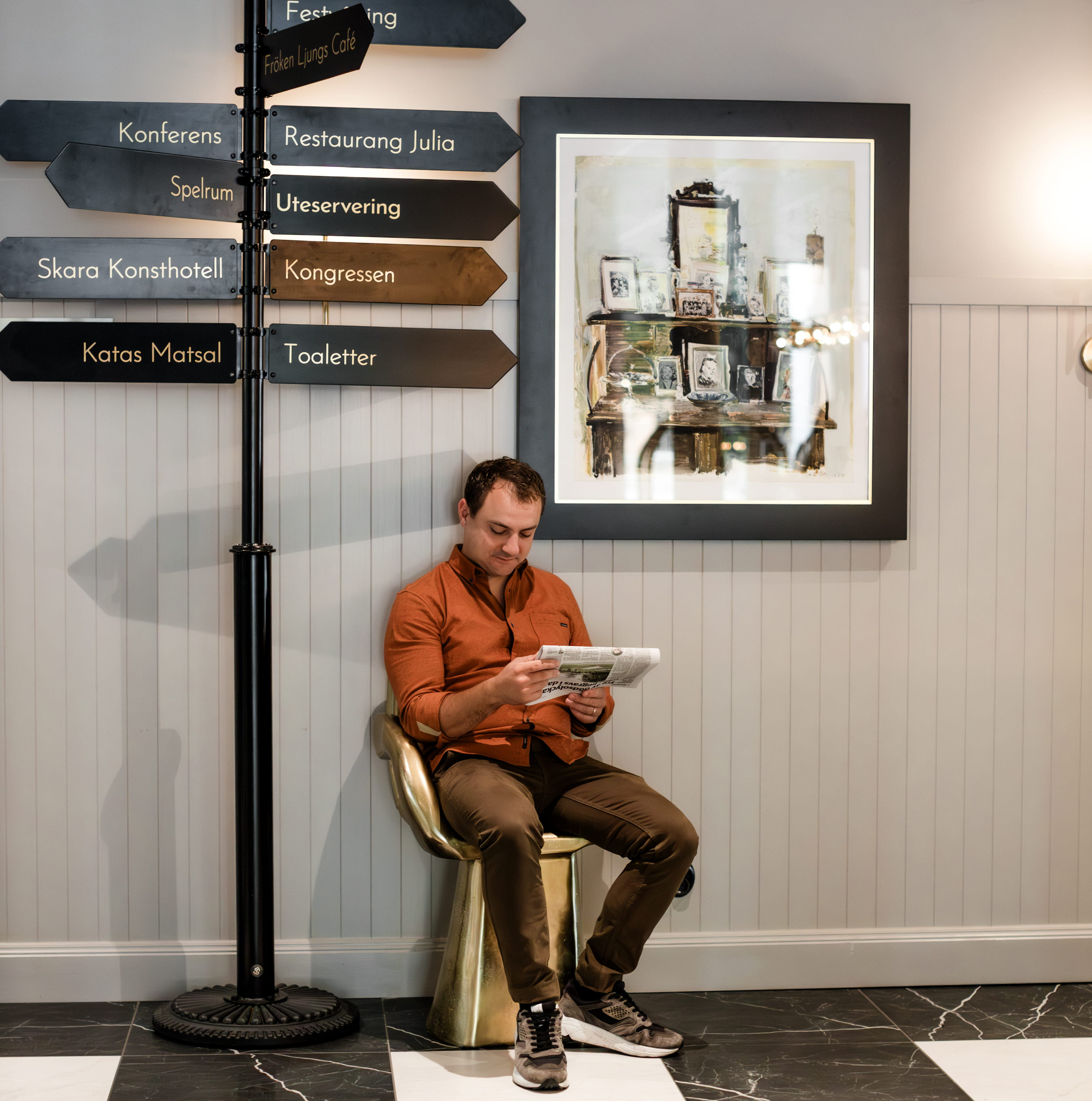 En man sitter på en stol och läser en tidning.