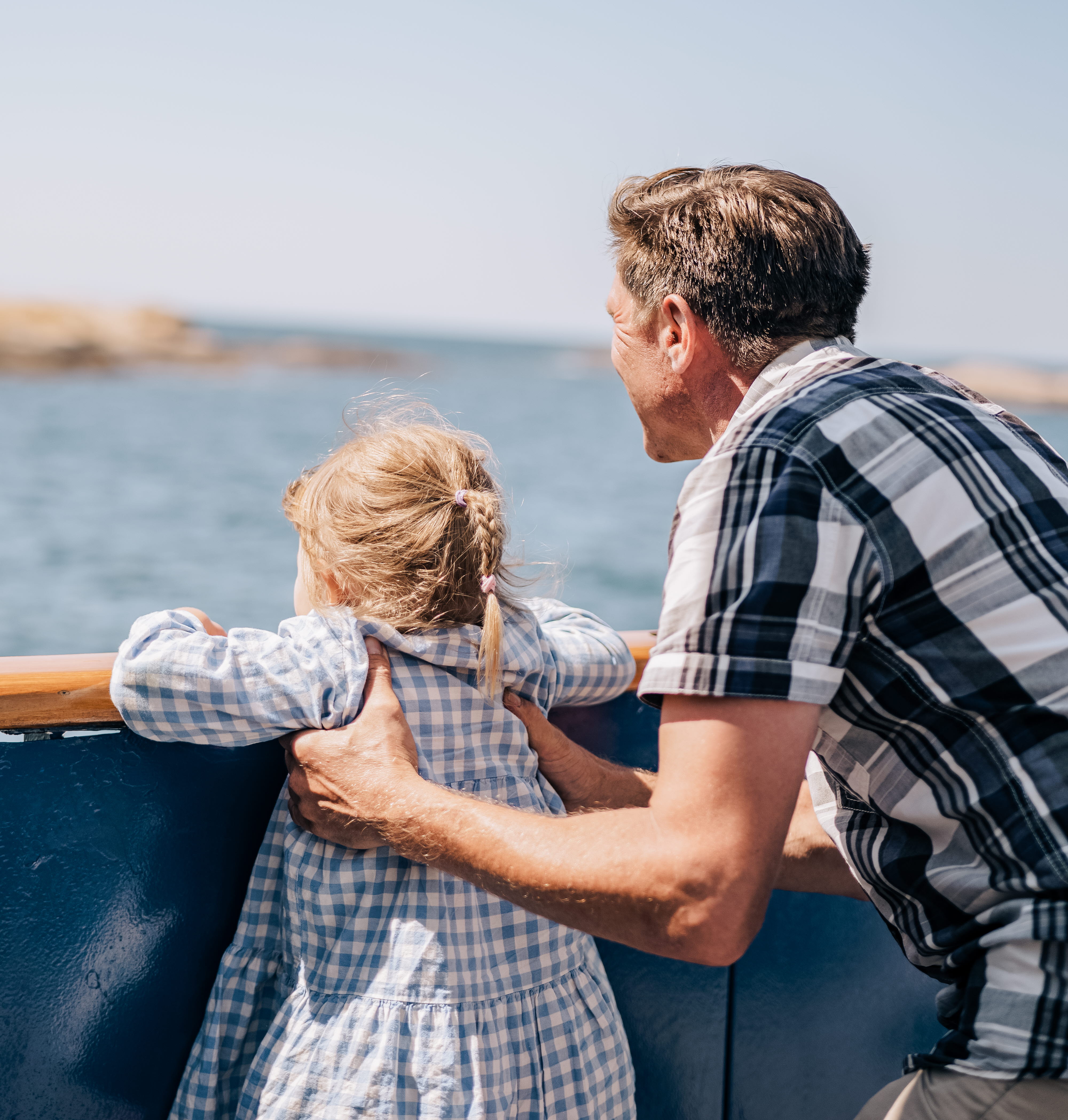 A man holds a little girl so she can look over a railing.