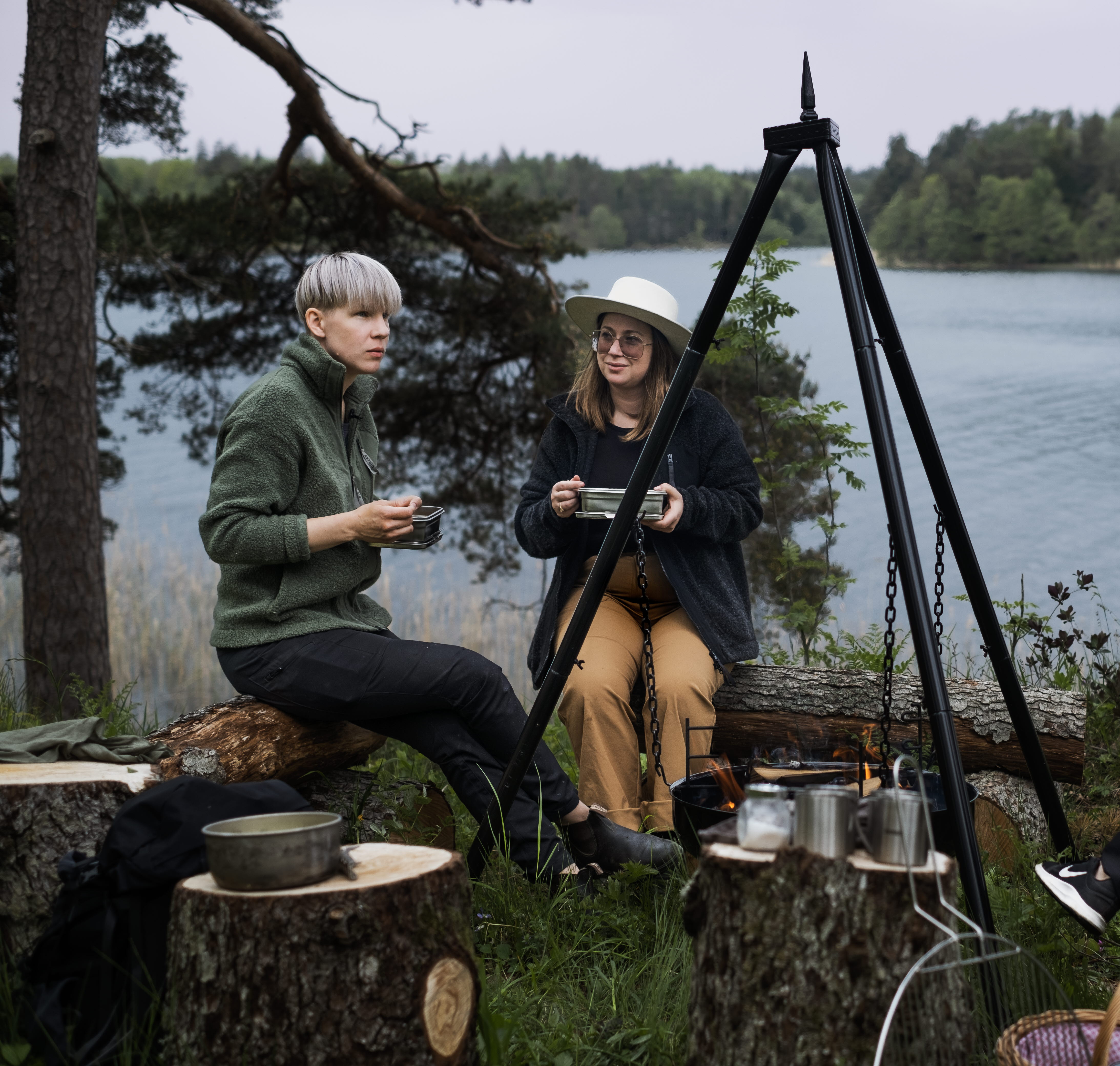 Vänner sitter runt eld och njuter av en måltid i Dalsland