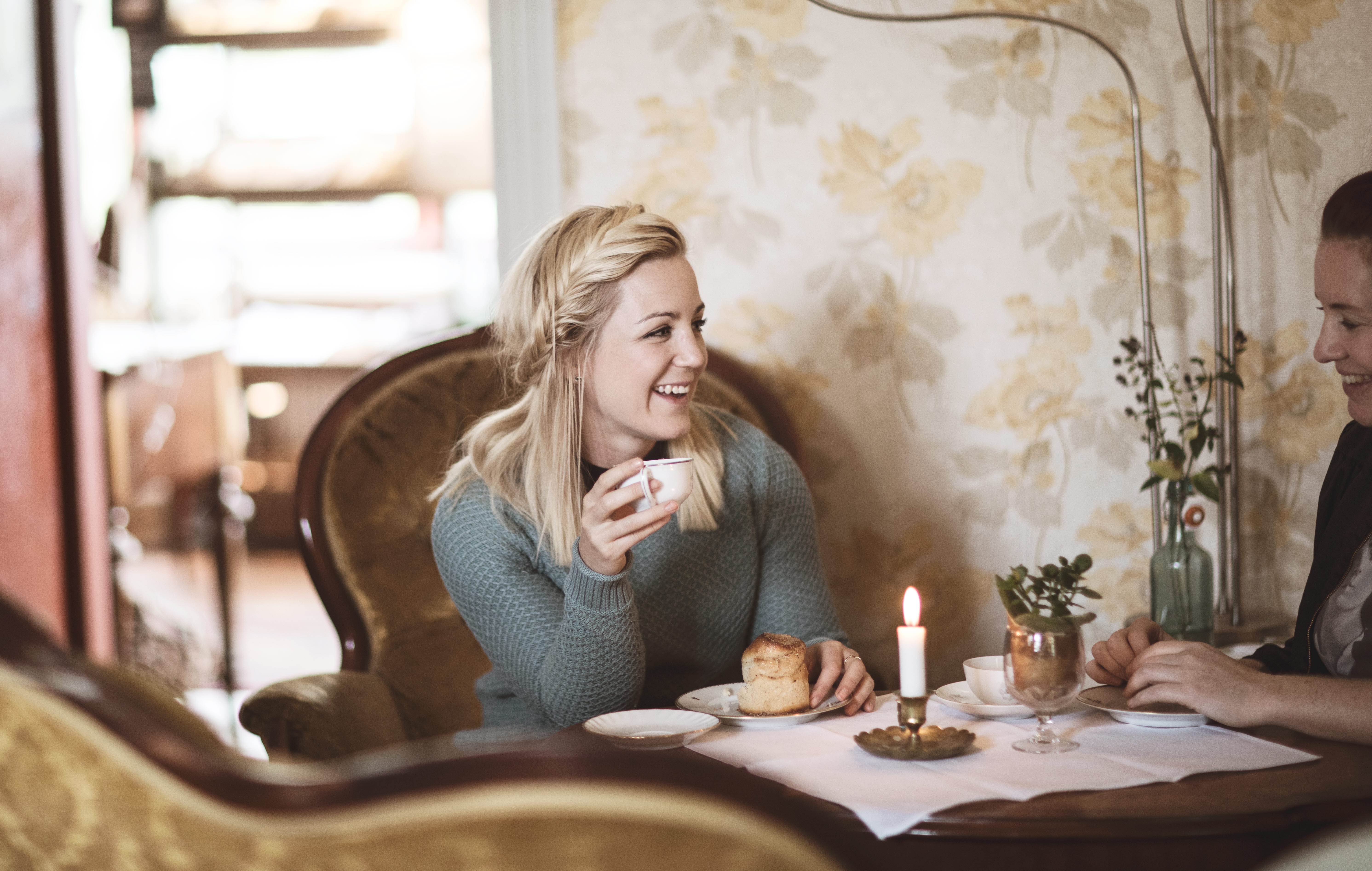 Kvinna fikar på kanelbulle och kaffe