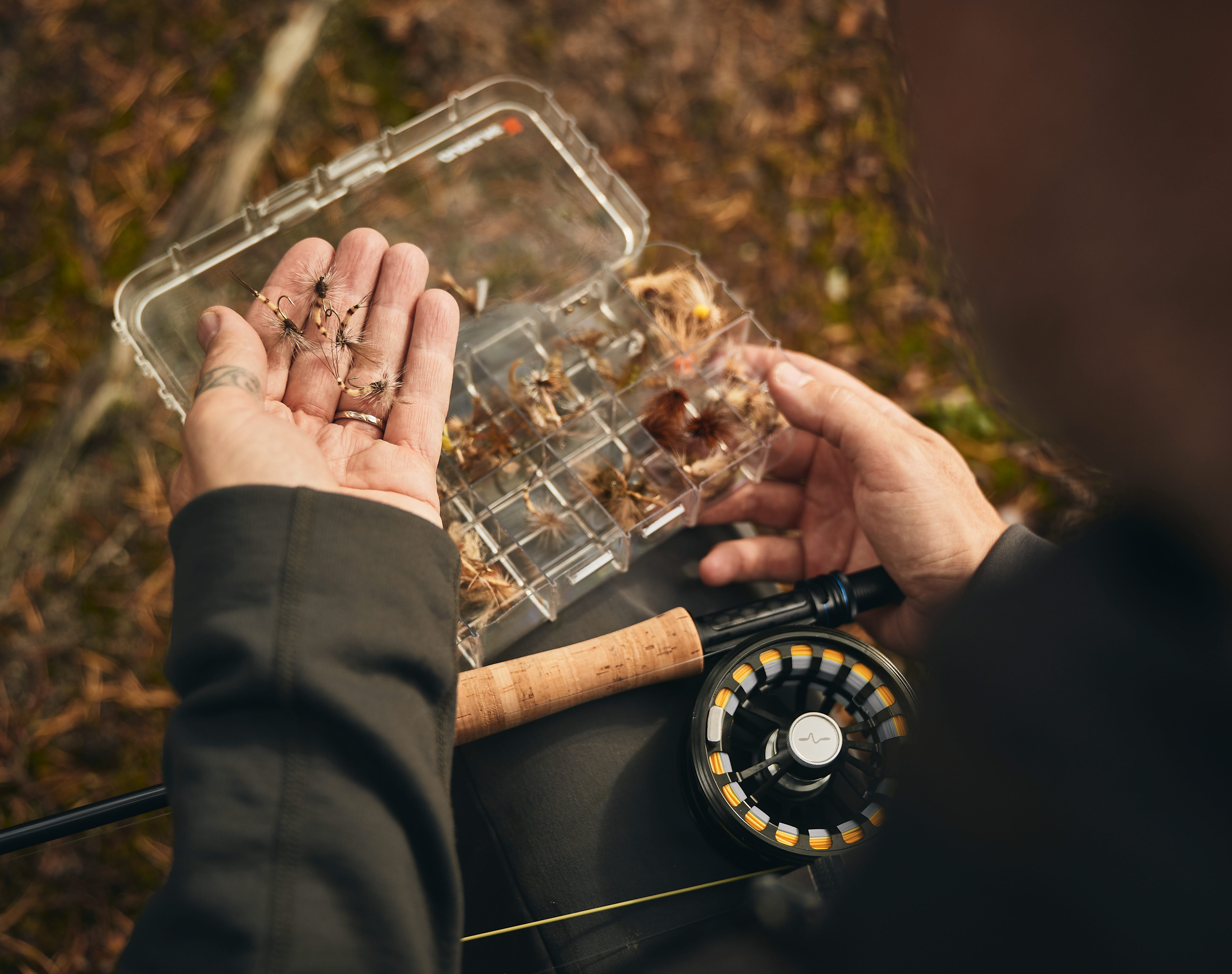 A man holds fishing accessories in his hand.